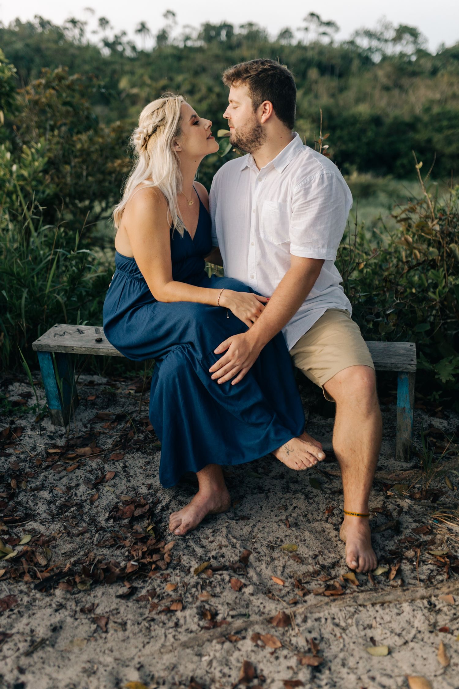 Couple sharing intimate moment while sitting on rocky outcrop surrounded by nature.
