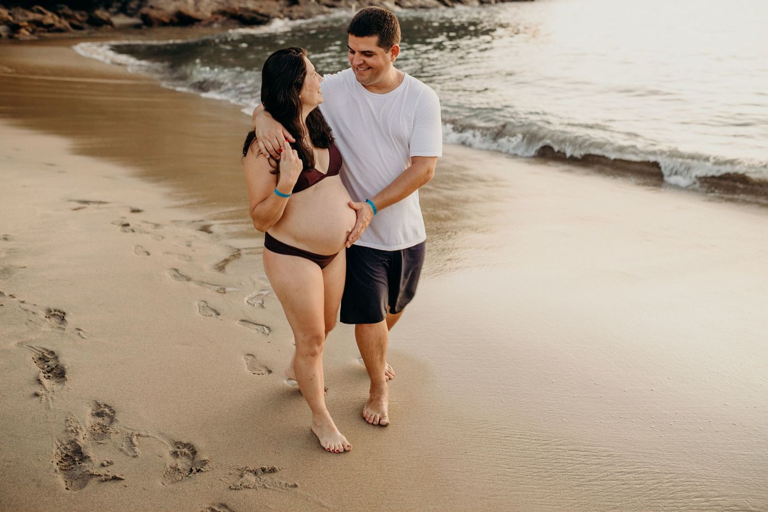 A couple enjoying a romantic walk along a sandy beach at sunset.