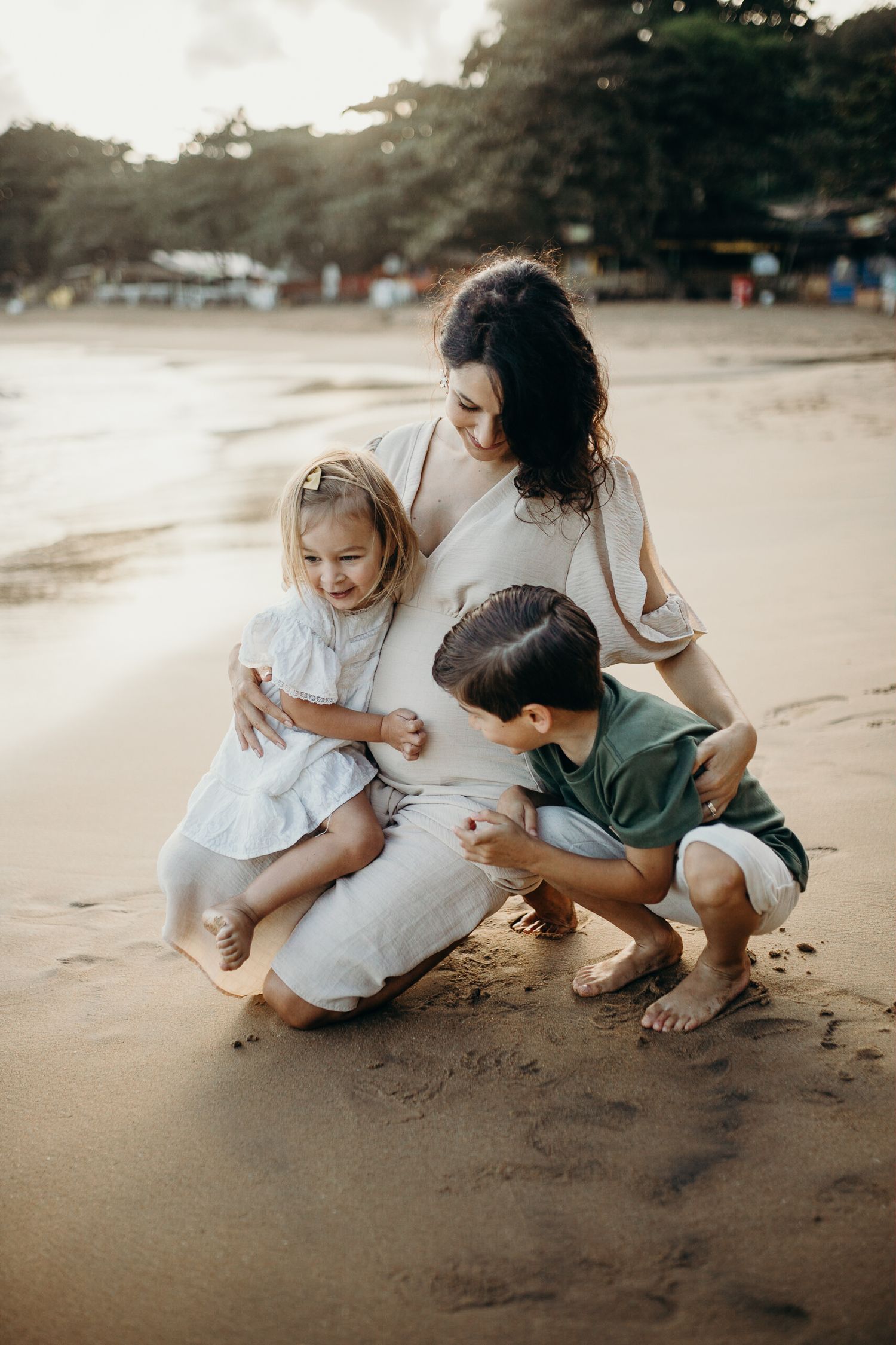 Tender family moment exploring the beach sand during golden hour.