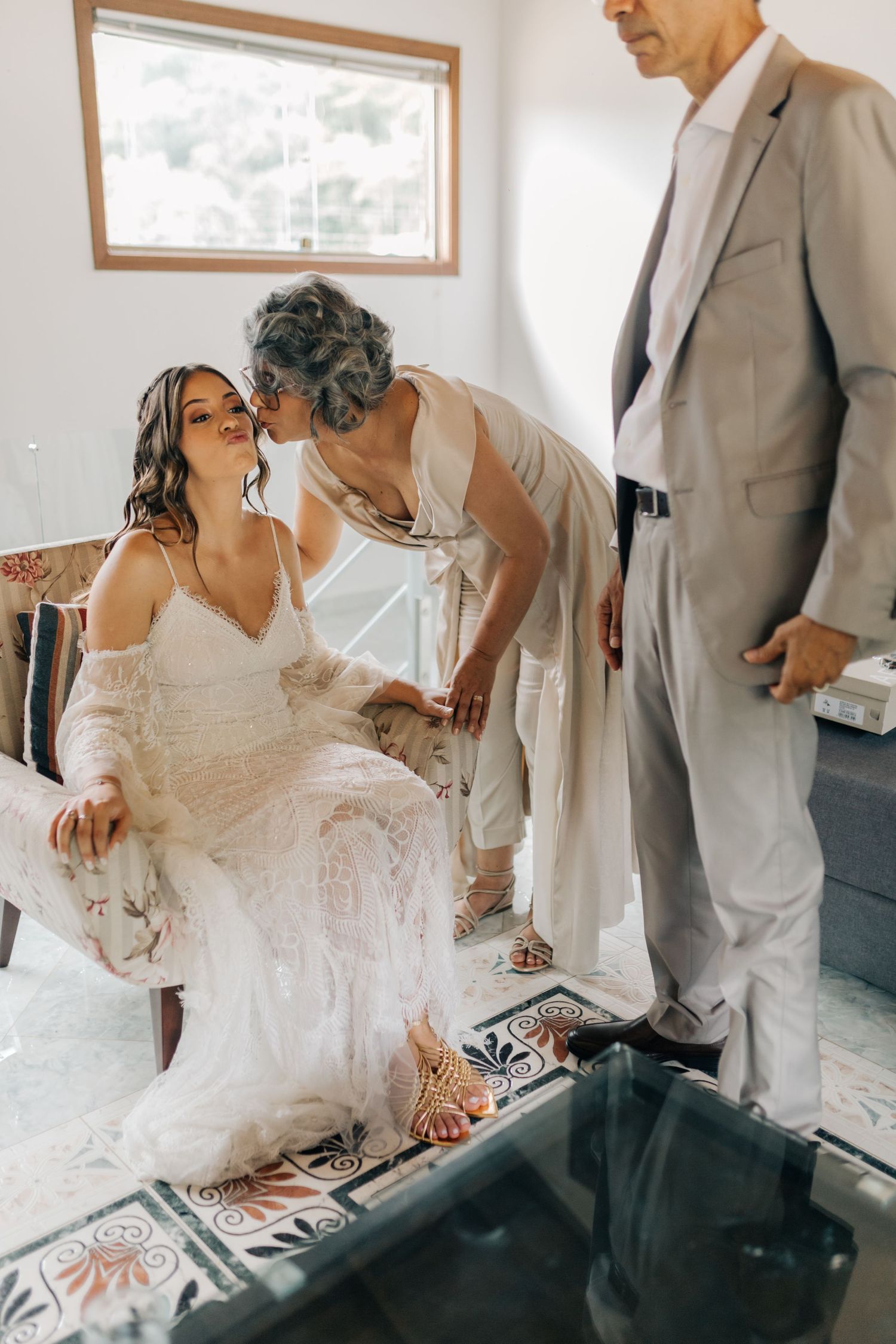 Intimate wedding preparation moment in bright room with window.