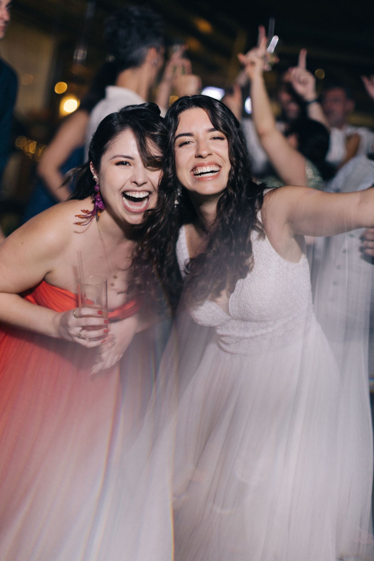 Two wedding guests share a joyful moment on the dance floor.