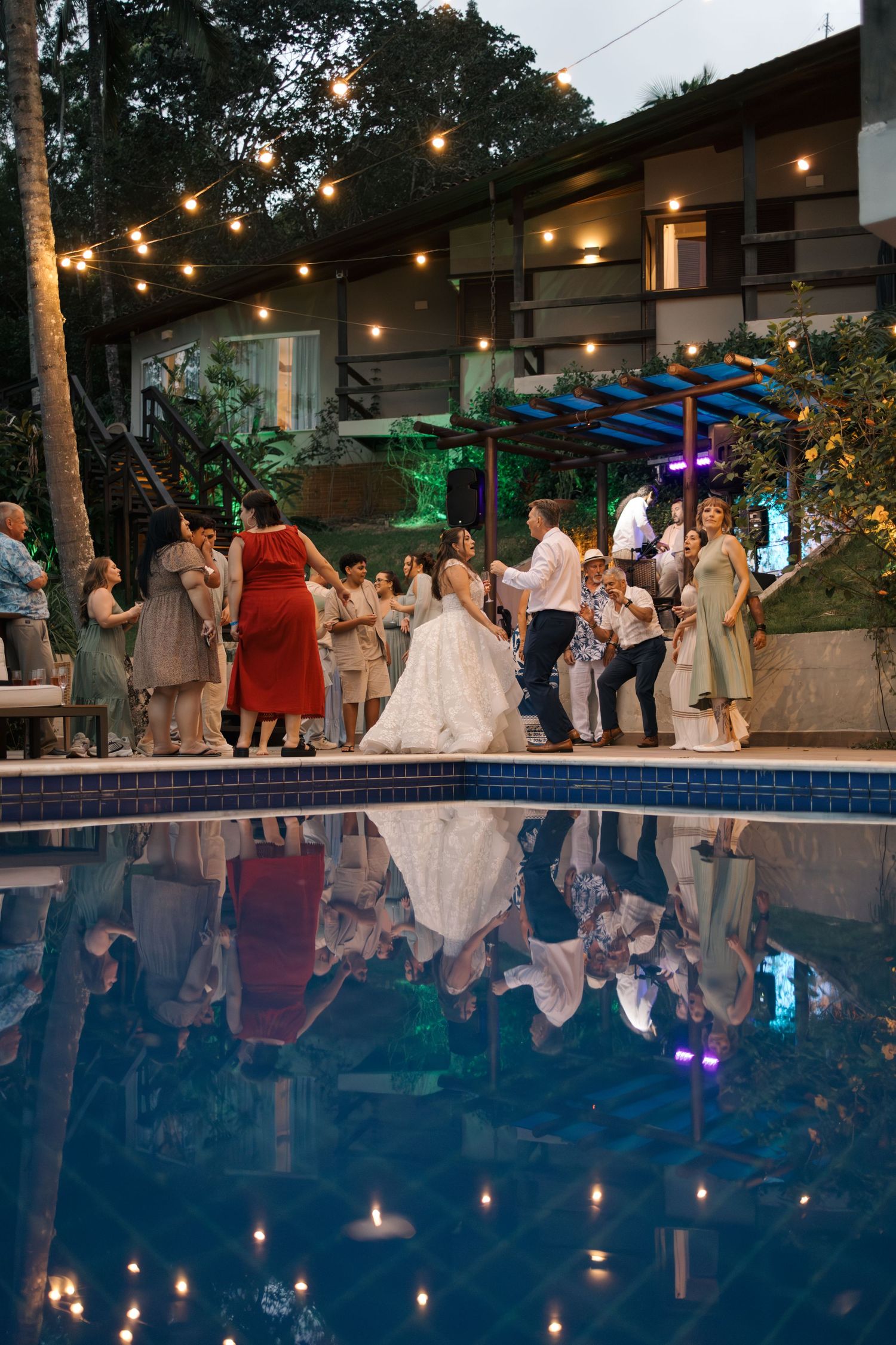Wedding reception by a pool at night with string lights creating a romantic atmosphere.