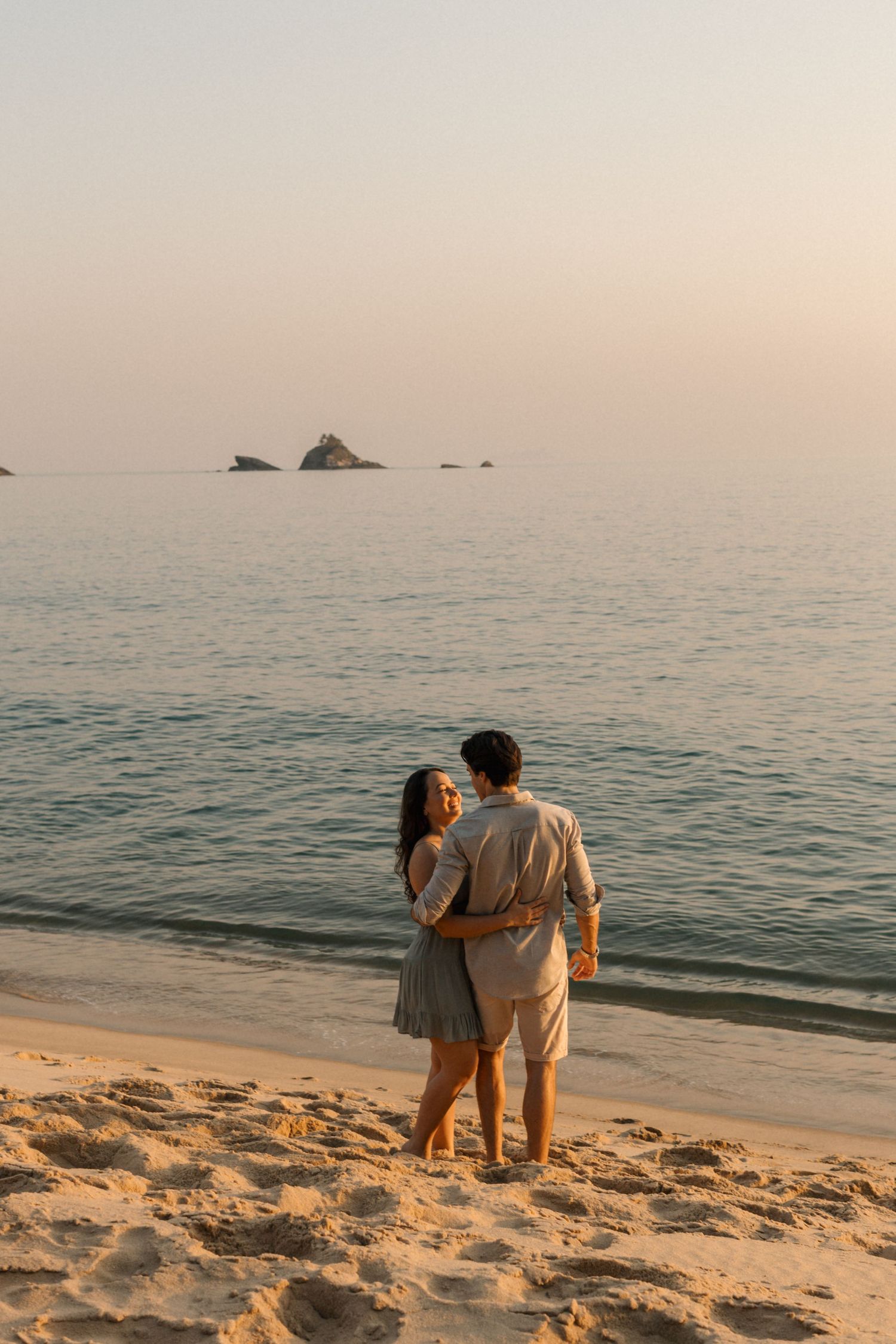 Couple enjoying a peaceful sunset moment together while walking along a sandy beach shore.