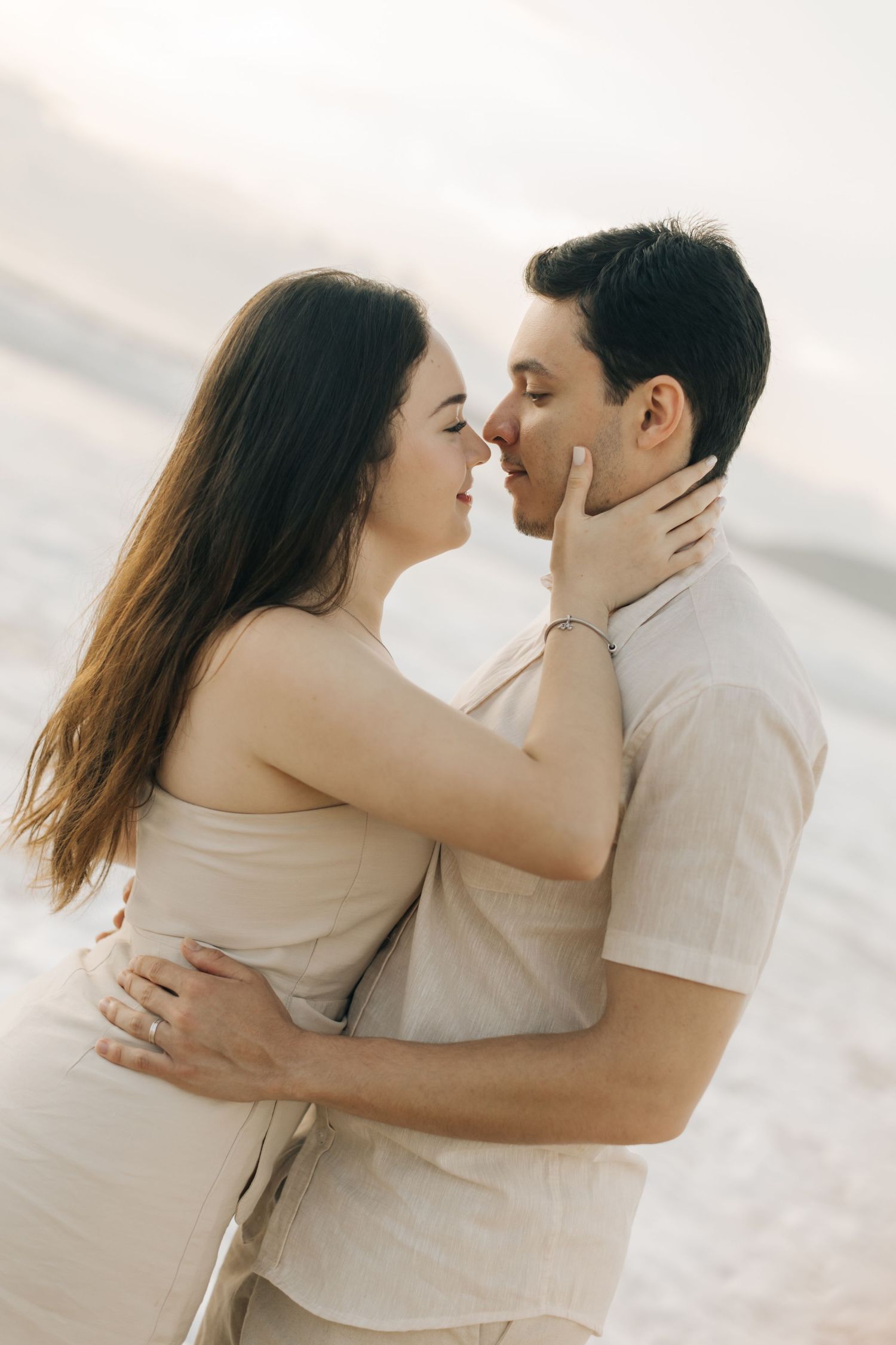 Intimate close-up of a couple sharing a tender moment on the beach at sunset.