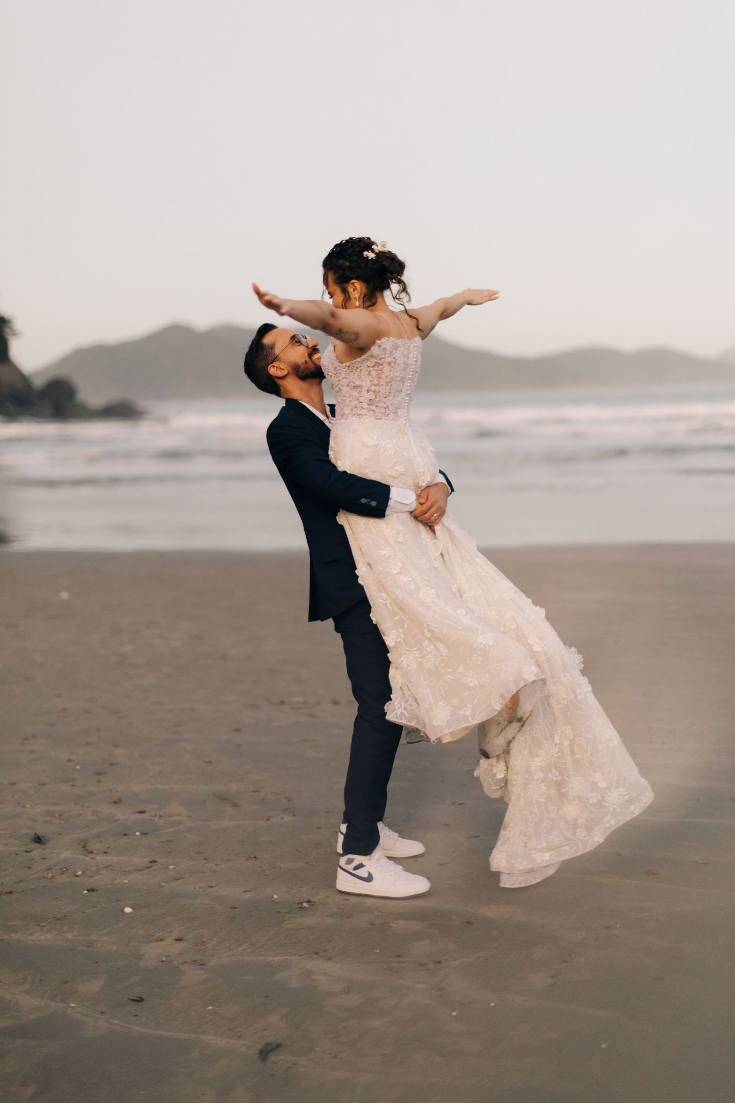 A romantic beach wedding moment with a couple dancing and embracing on the sand.
