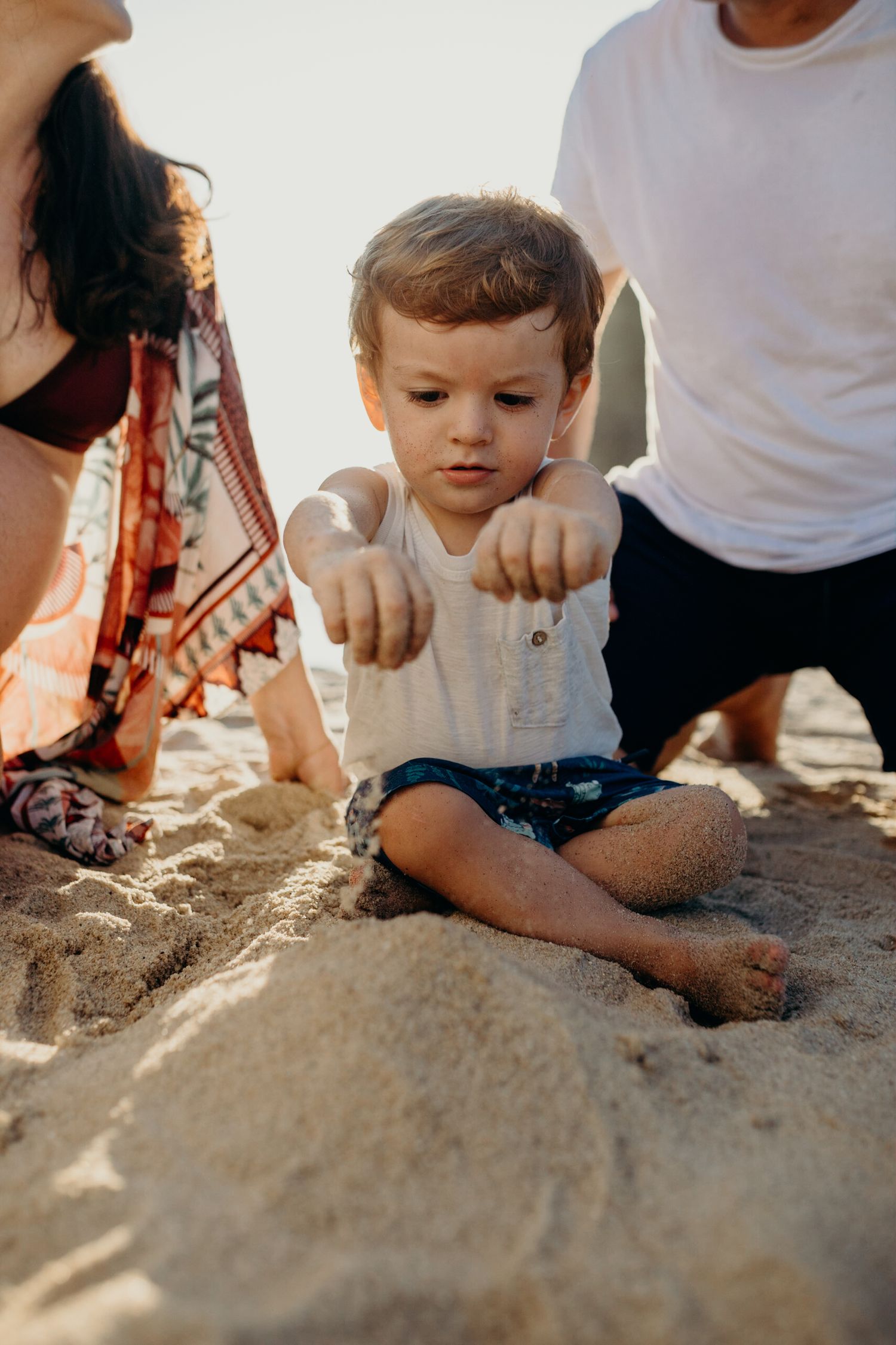 People playing and digging in golden beach sand during sunset.