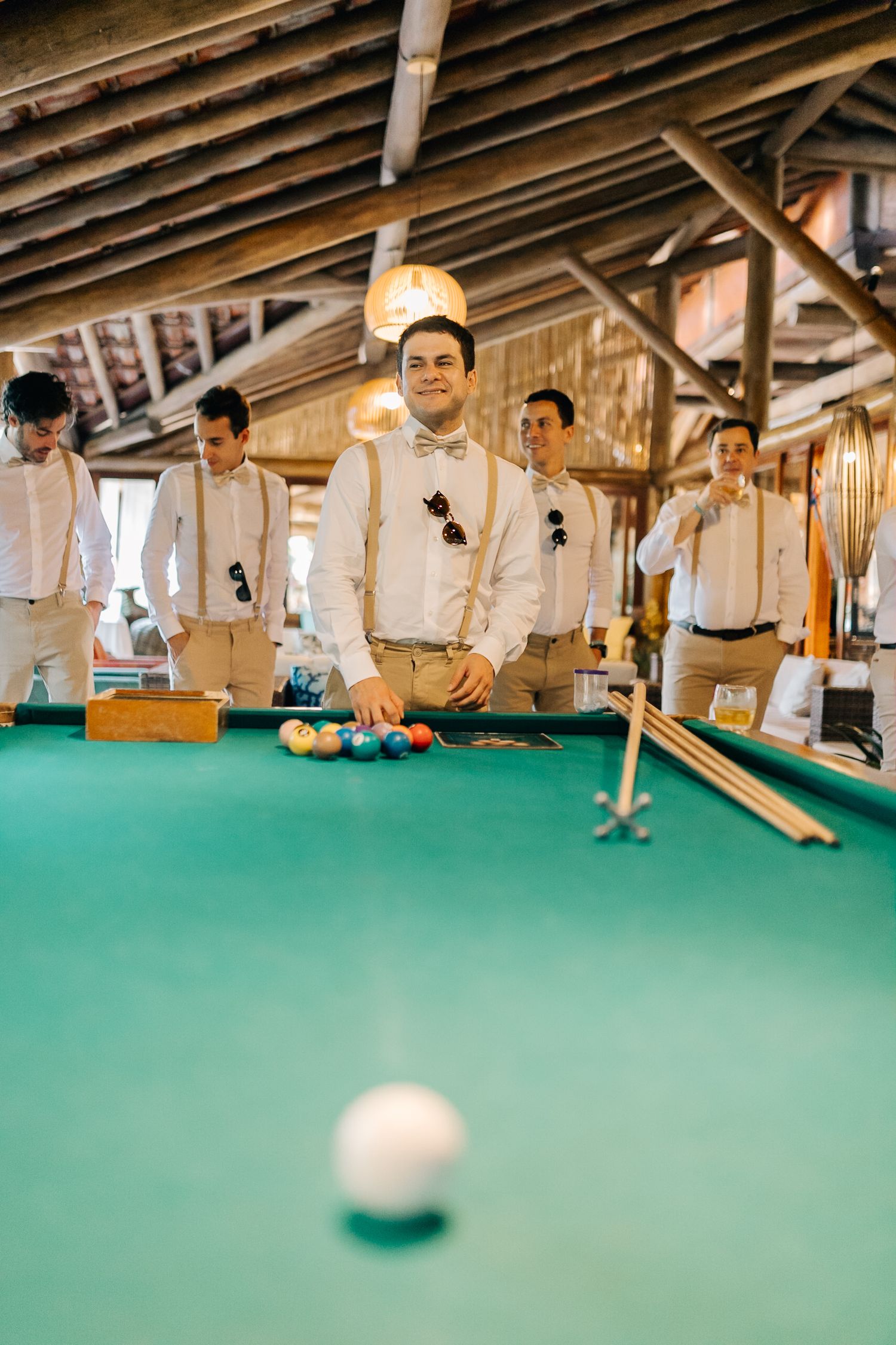 Series of shots showing a pool game in progress on a green felt table with exposed wooden ceiling beams.