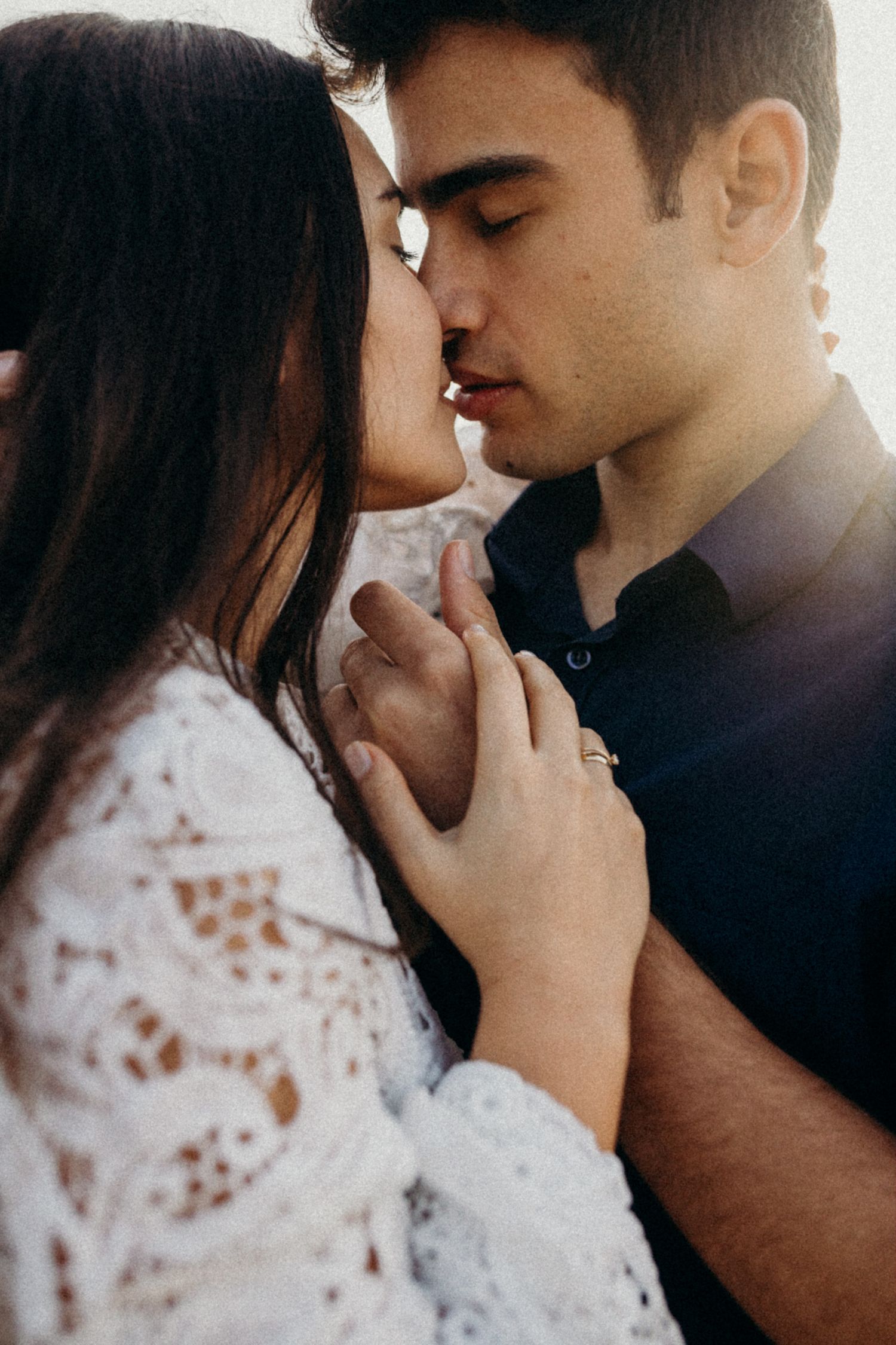 Intimate close-up portraits of a couple in white lace and navy sharing tender moments.