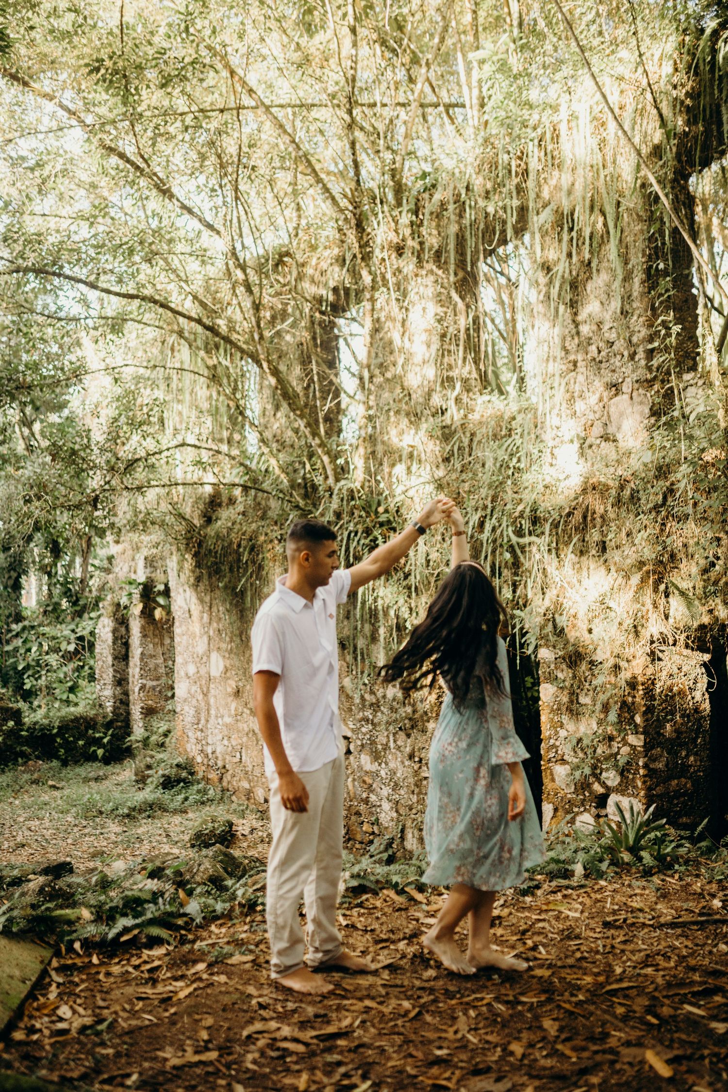 Two people dancing together under moss-draped trees in a magical forest setting.