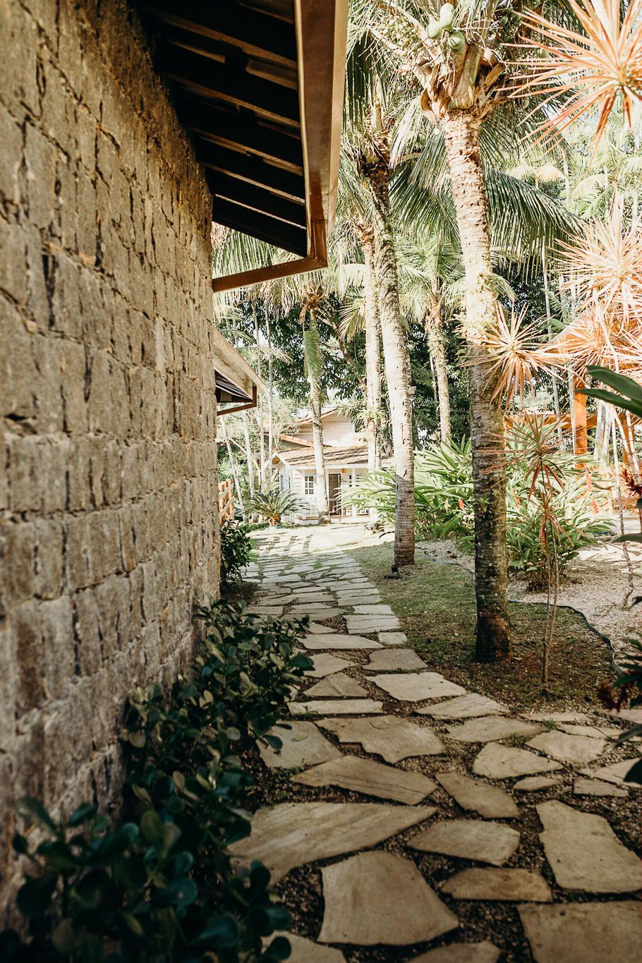A stone pathway winds through palm trees and tropical landscaping.