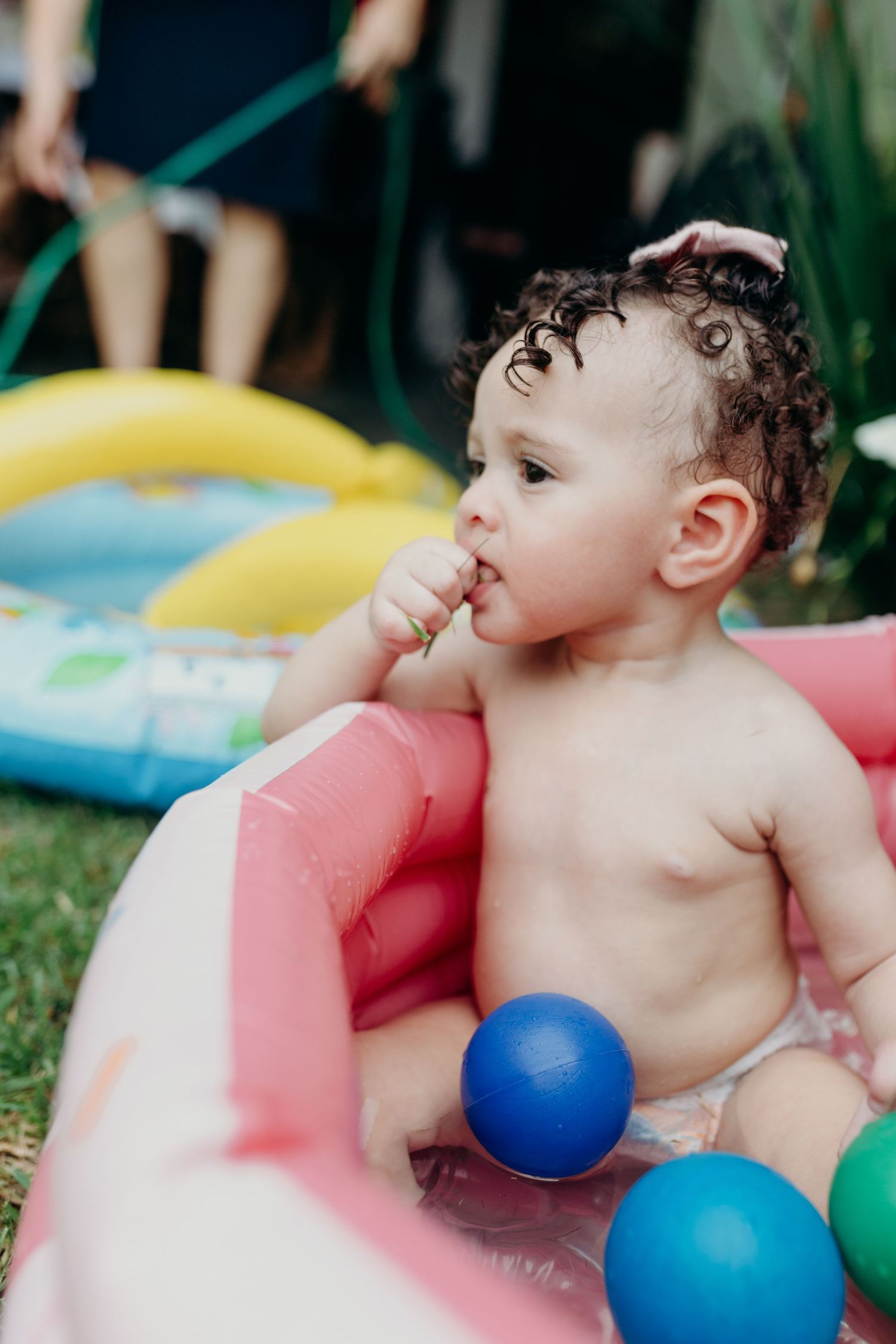 Pink inflatable kiddie pool with colorful balls for summer play.