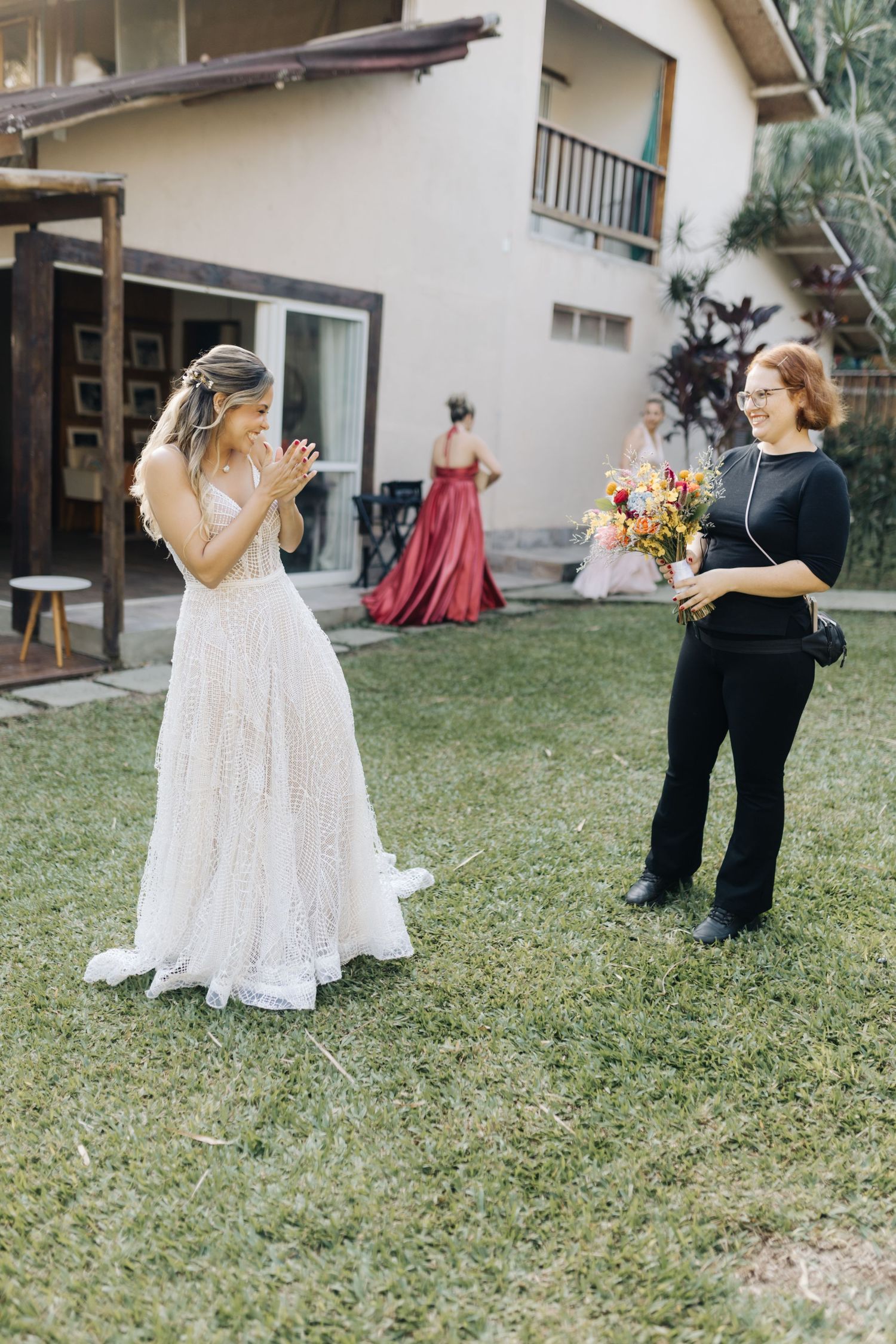 Wedding photography session taking place on a grassy lawn with guests in background.