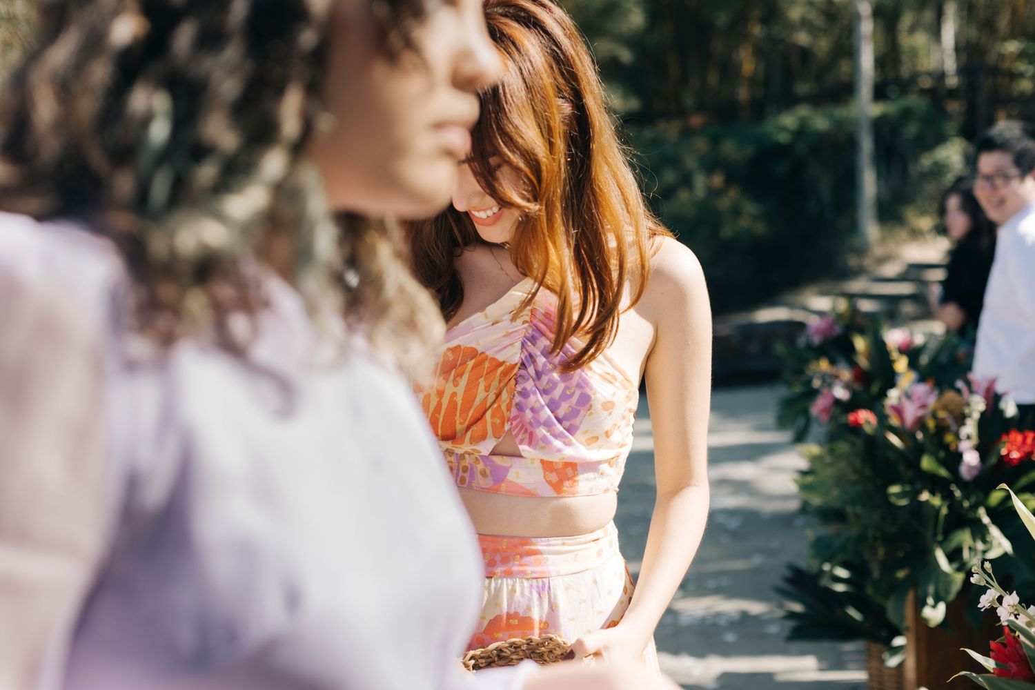 Close-up shot of wedding guests in pastel and floral attire at an outdoor celebration.
