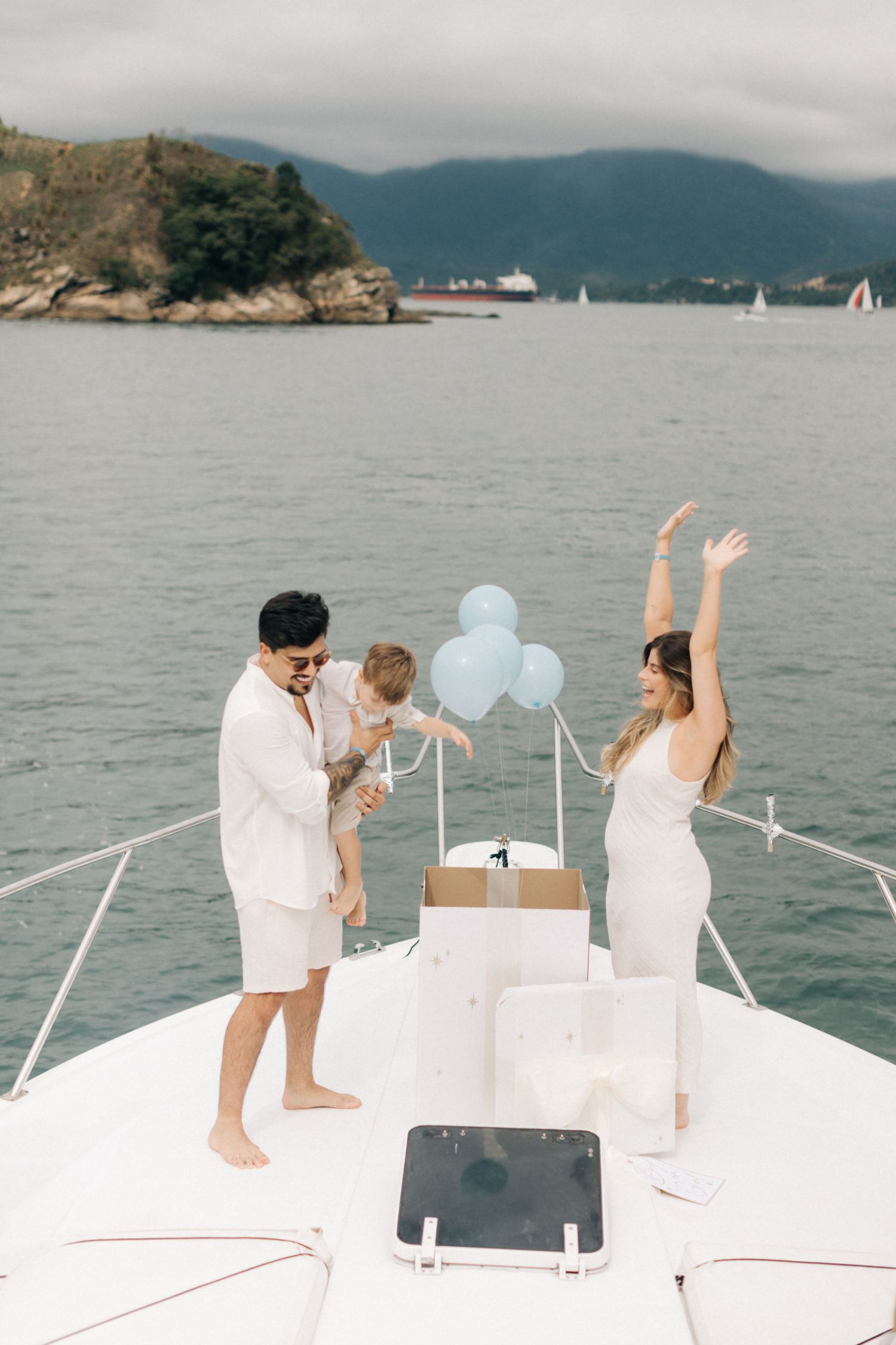 A special moment unfolds on a yacht deck with blue balloons and mountain views.