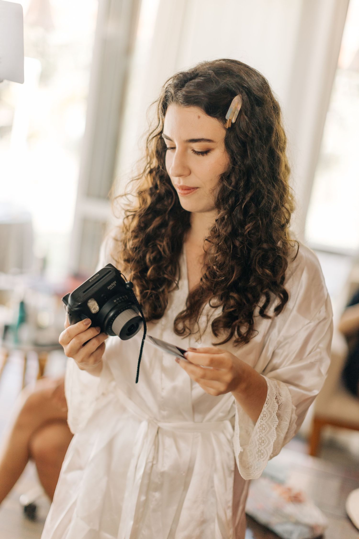 Woman in silk robe examining vintage camera while getting ready.