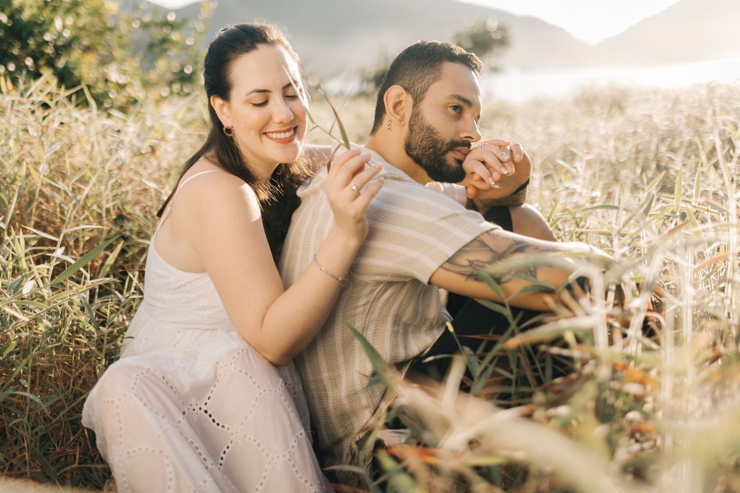 Couple sharing romantic moment in golden field during sunset photoshoot.