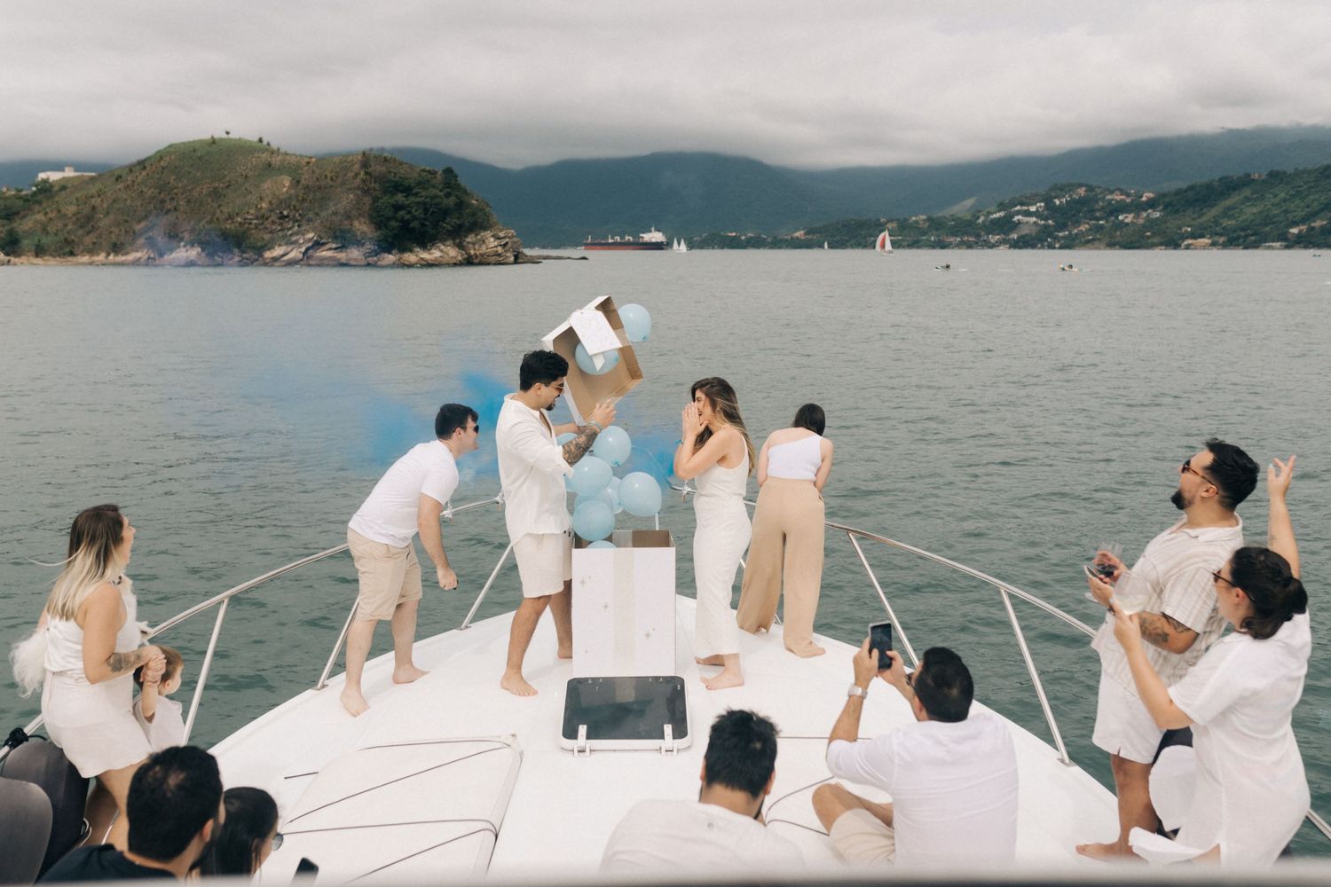 Guests aboard a white yacht enjoying views of a mountainous harbor.