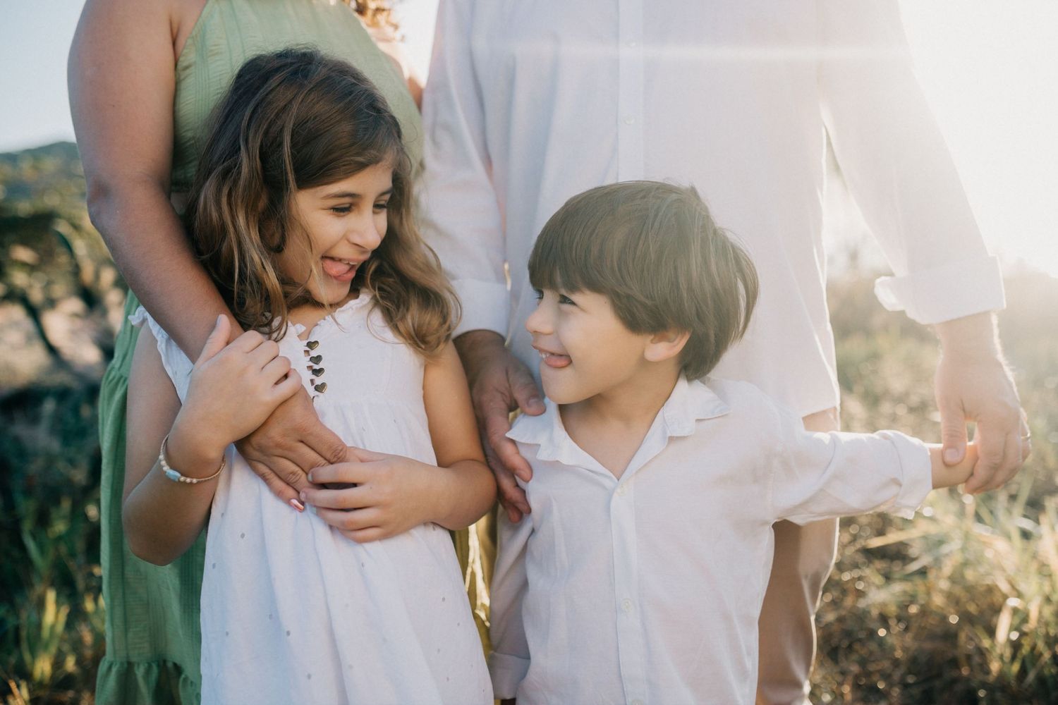 Two children smile and play together during an outdoor family photoshoot.