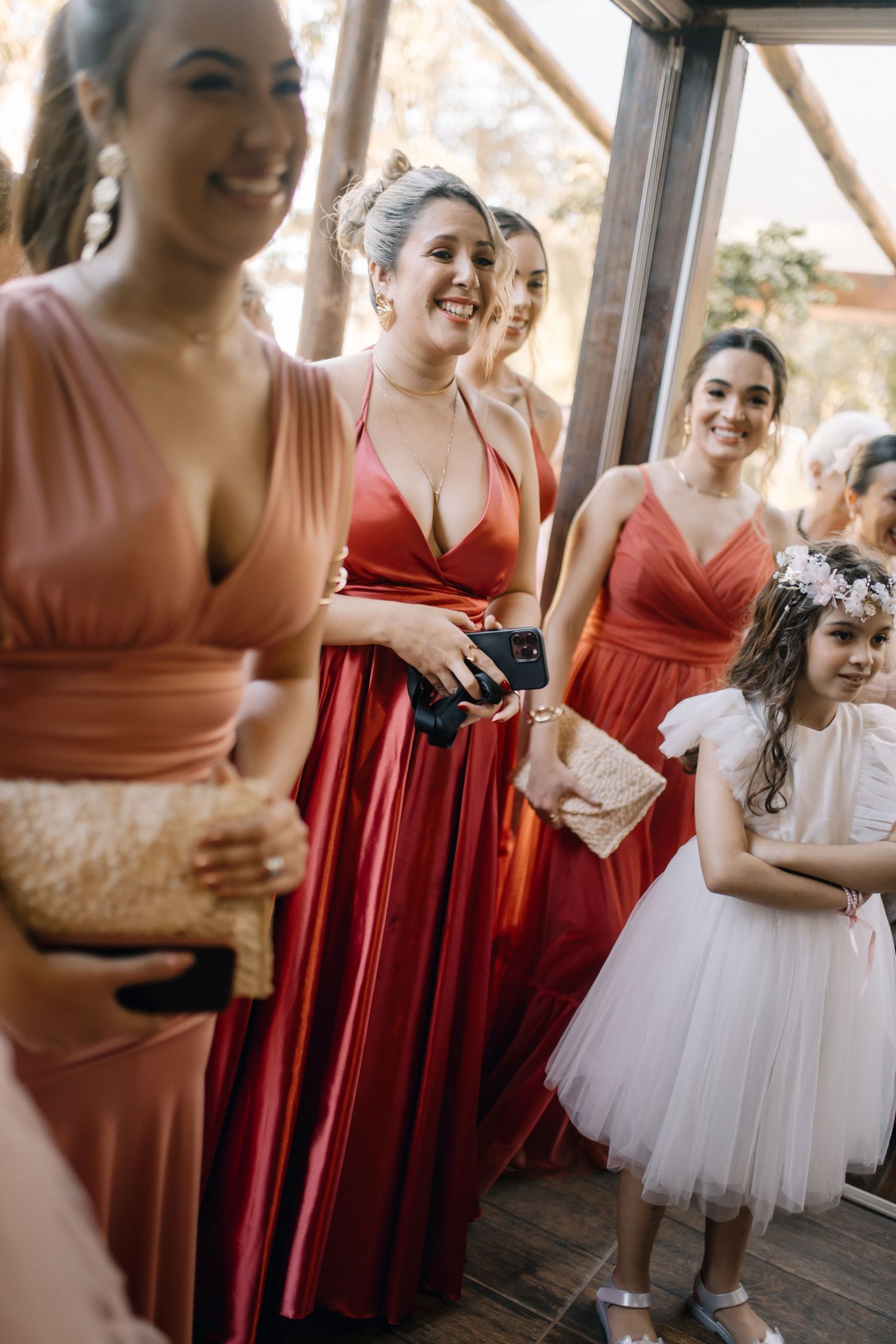 Bridesmaids in coral dresses and flower girl in white share a joyful moment at wedding.
