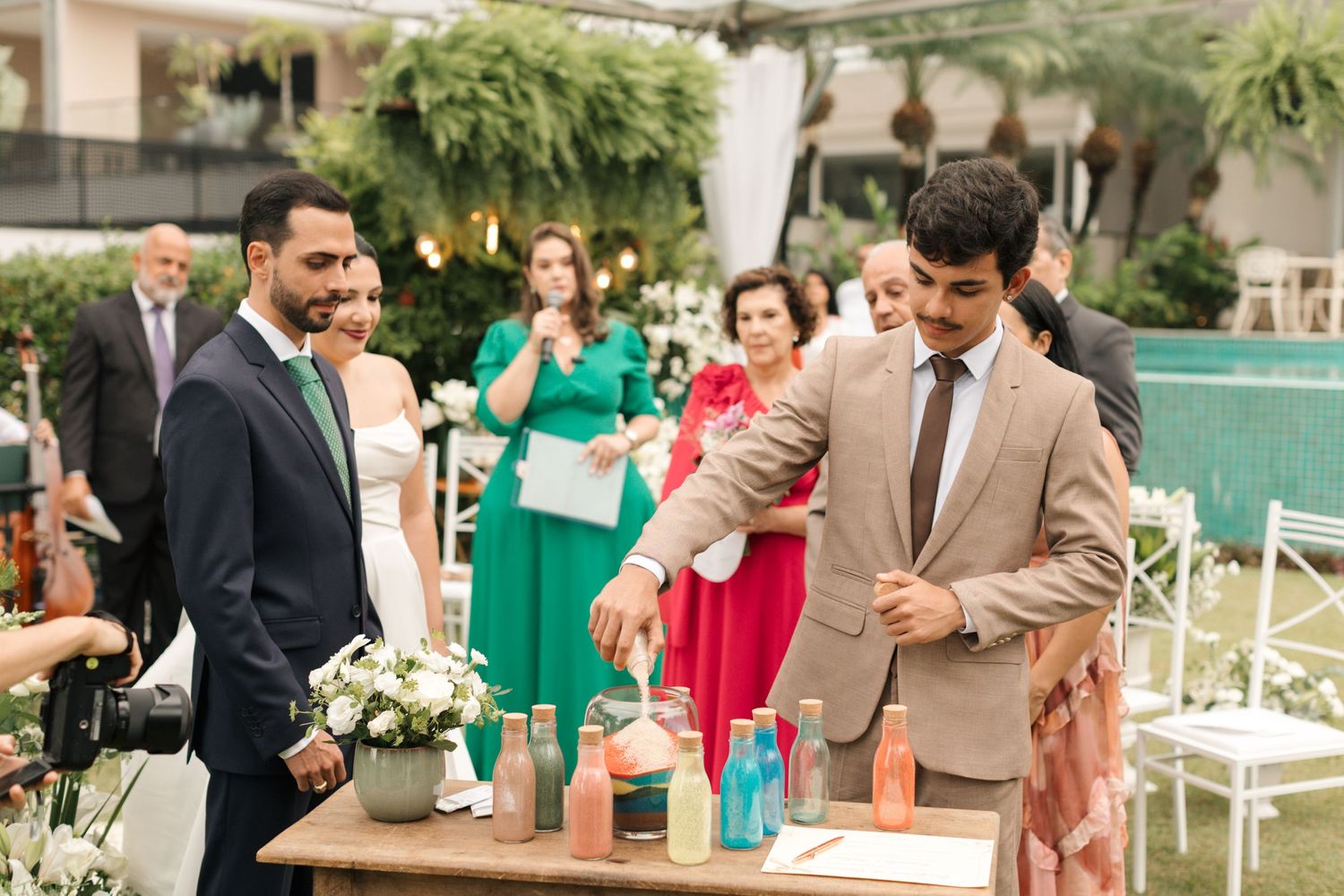 Wedding party celebrating with colorful sand art ceremony displays at outdoor reception.