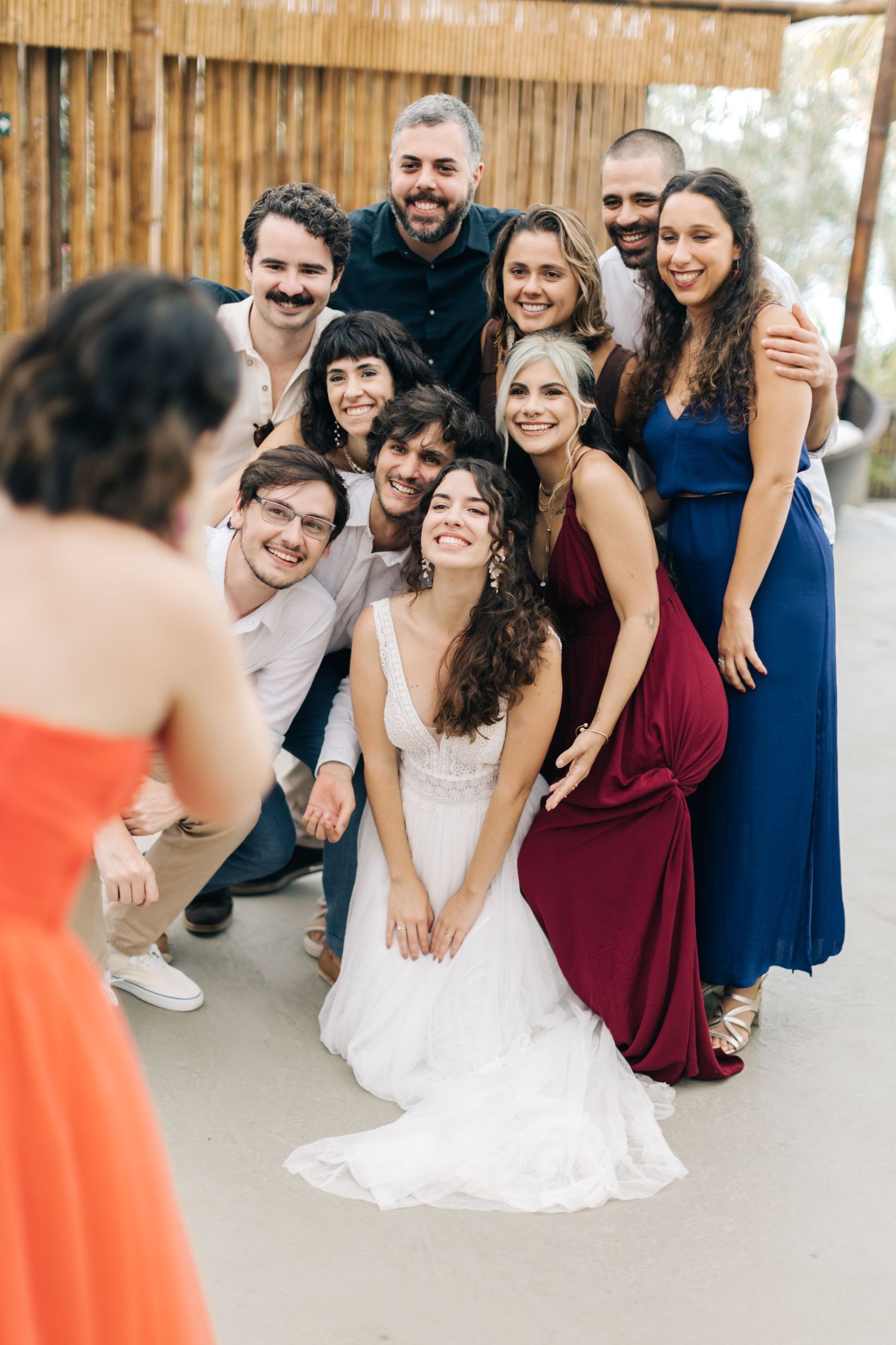 Wedding party poses together for group photo in front of rustic wooden backdrop.