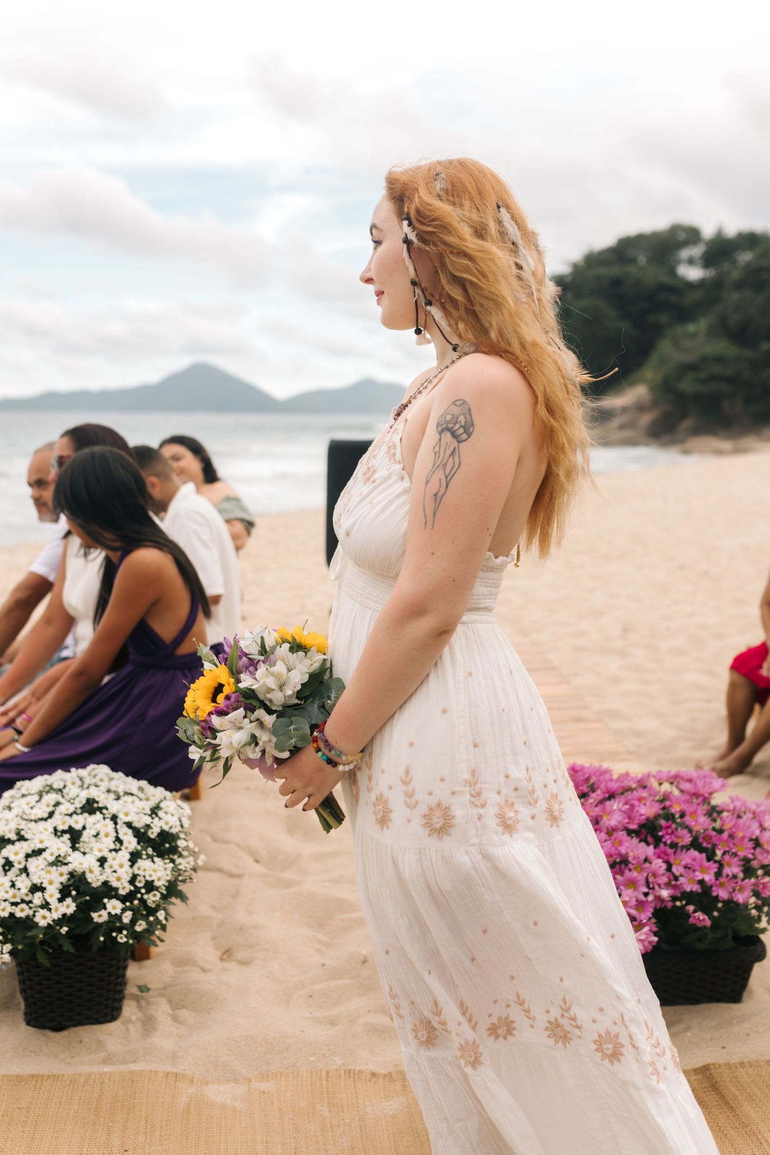 A seaside wedding scene with potted flowers and mountains in the background.