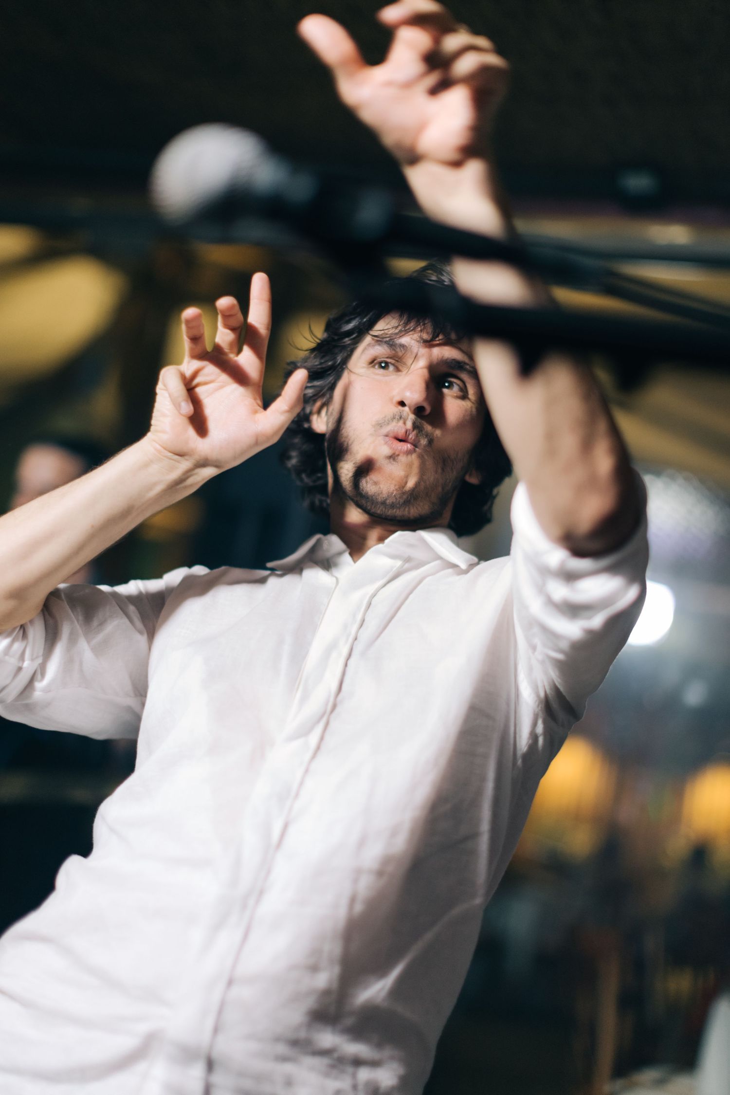 Performer in white button-up shirt dances expressively during show.