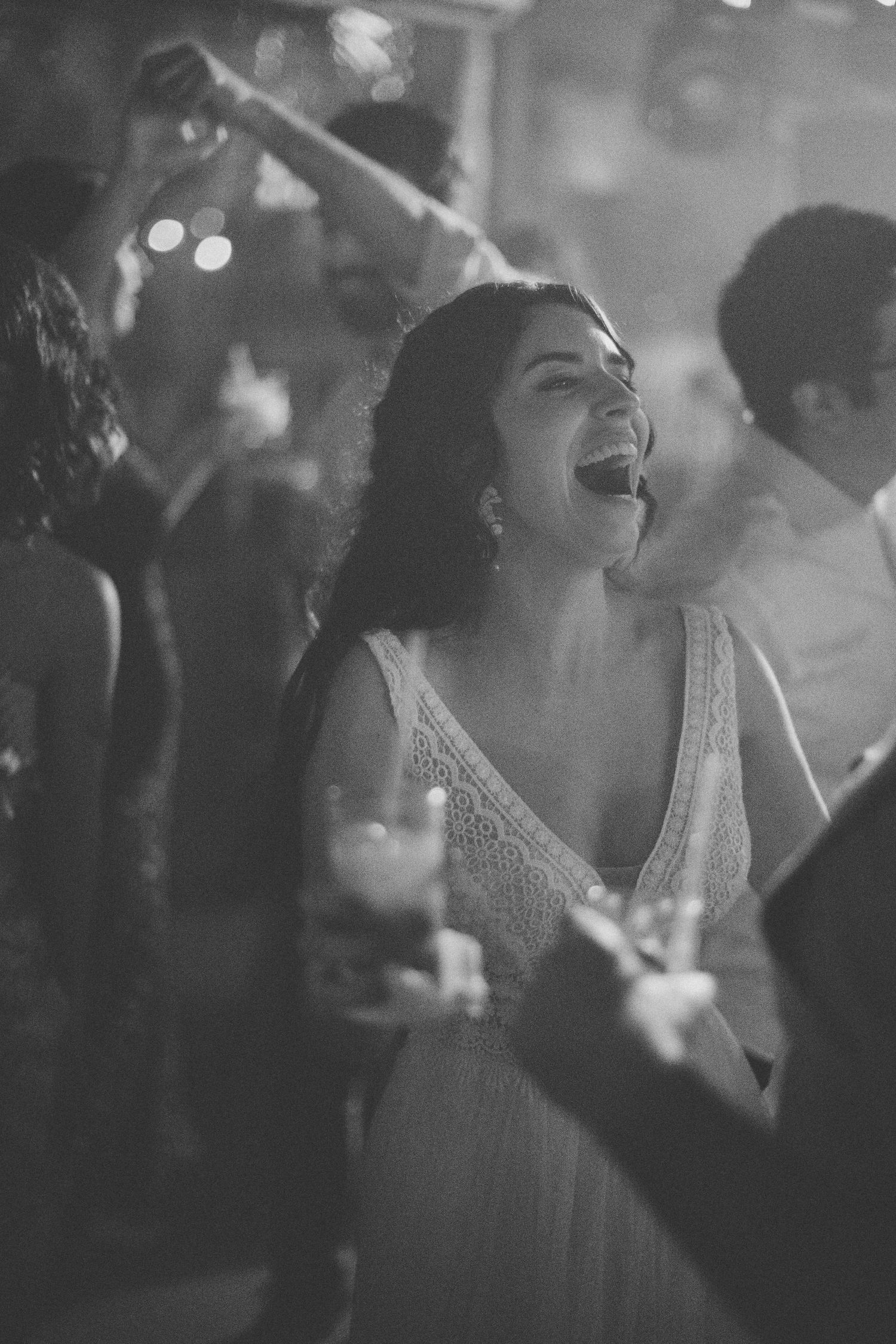 Wedding guests dancing joyfully at a reception with dramatic lighting creating a festive atmosphere.