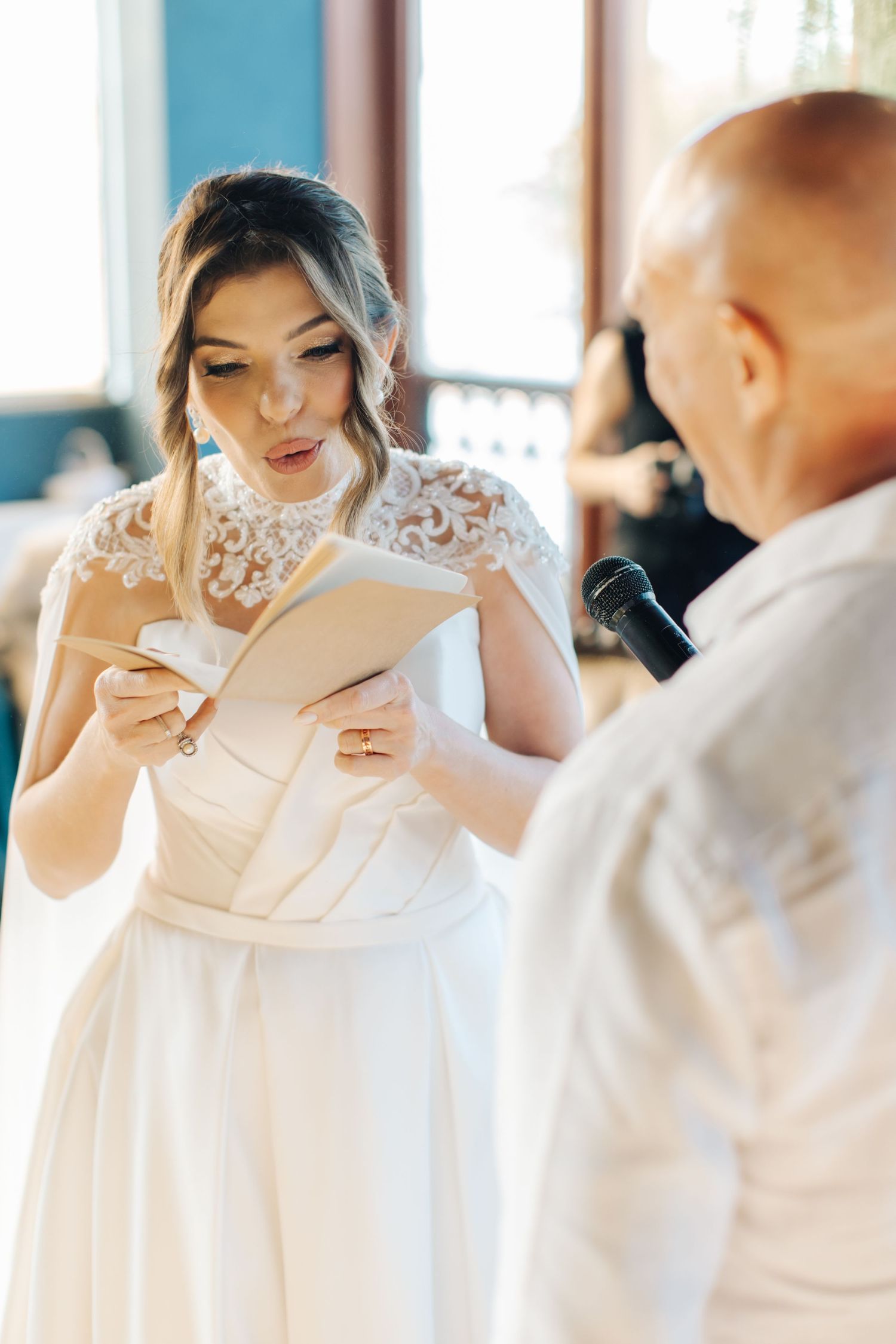 Wedding ceremony with bride reading vows in elegant lace dress.