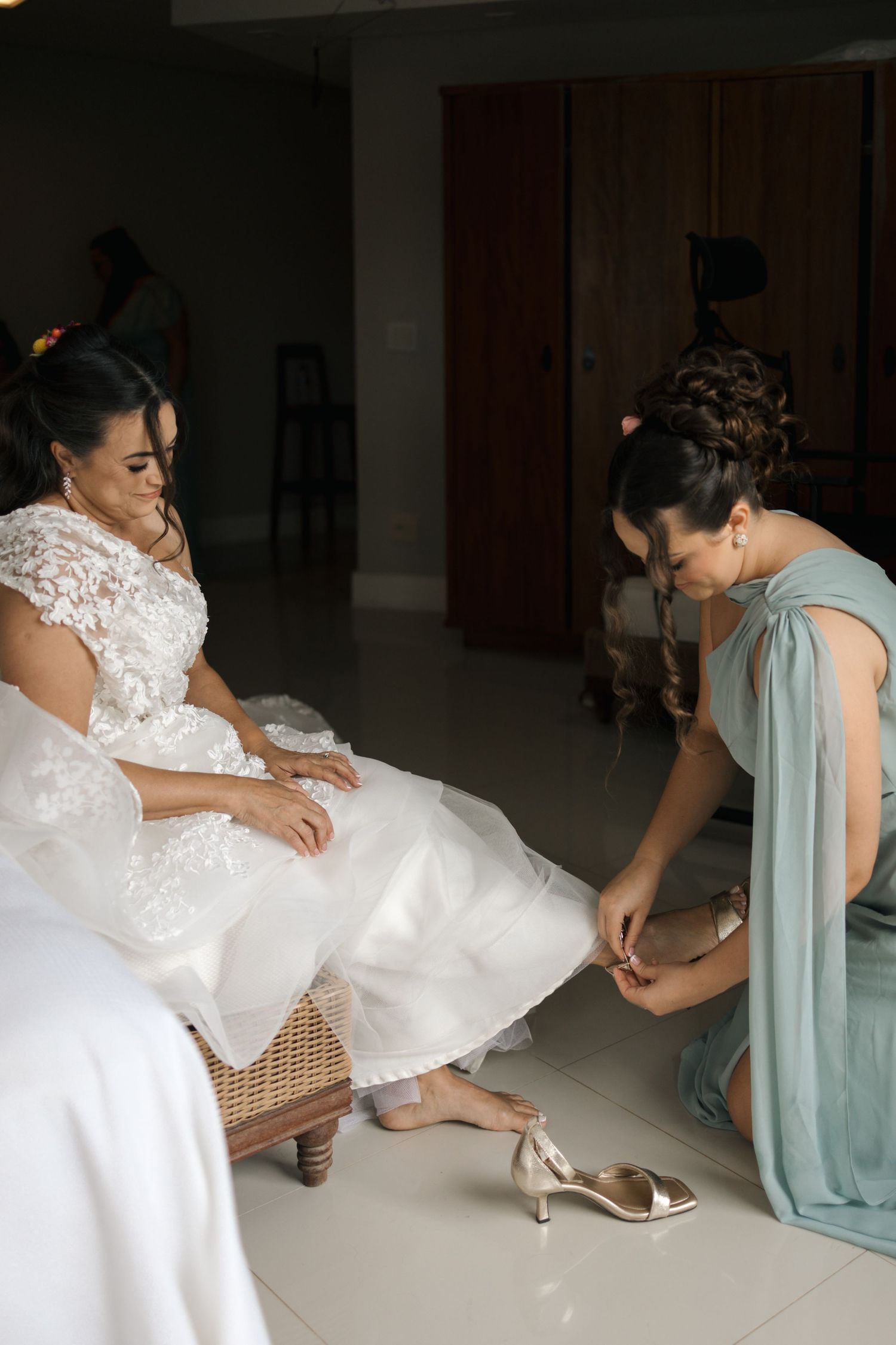 Series of photos showing someone adjusting a white wedding dress and shoes during preparation.