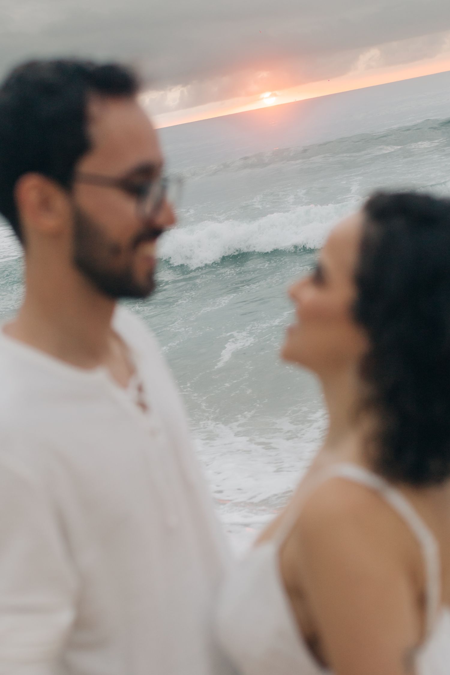 A romantic couple shares a joyful moment on the beach at sunset.