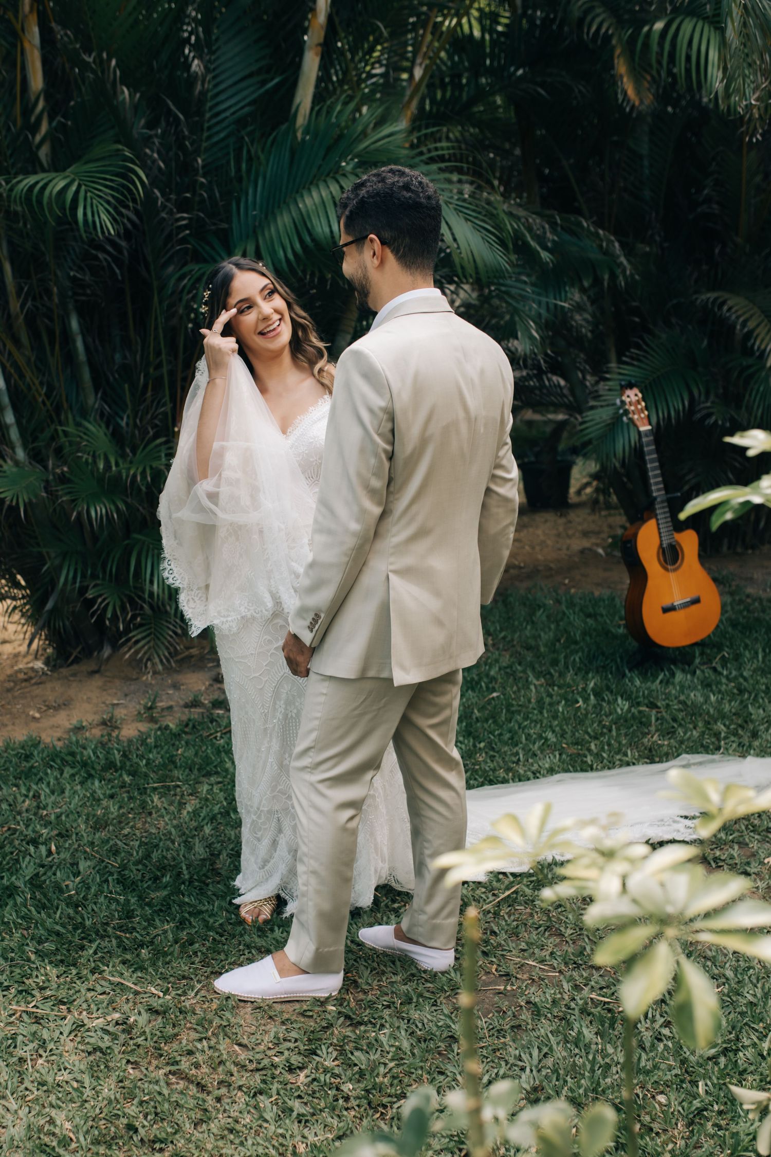 Garden wedding portrait with tropical foliage and acoustic guitar as backdrop decorations.
