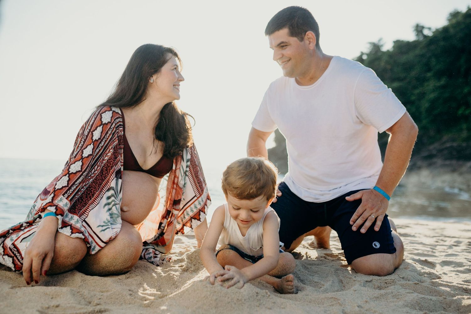 Family relaxing together on sandy beach with ocean view.