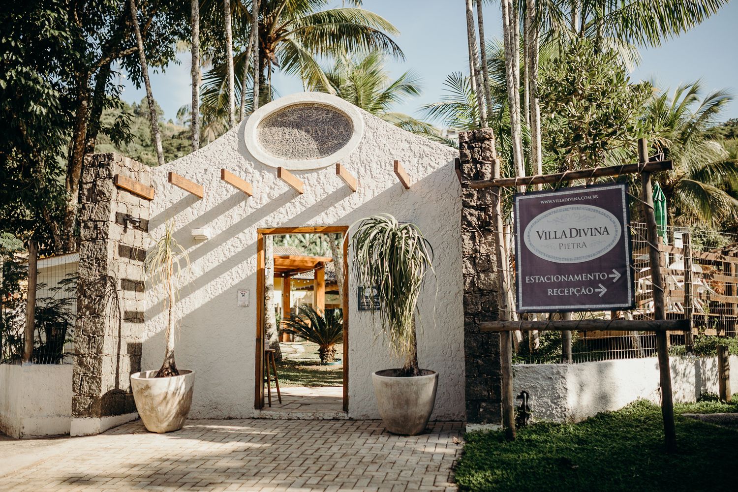 White arched entrance with Villa Capponi sign and tropical palm trees at a luxury resort.