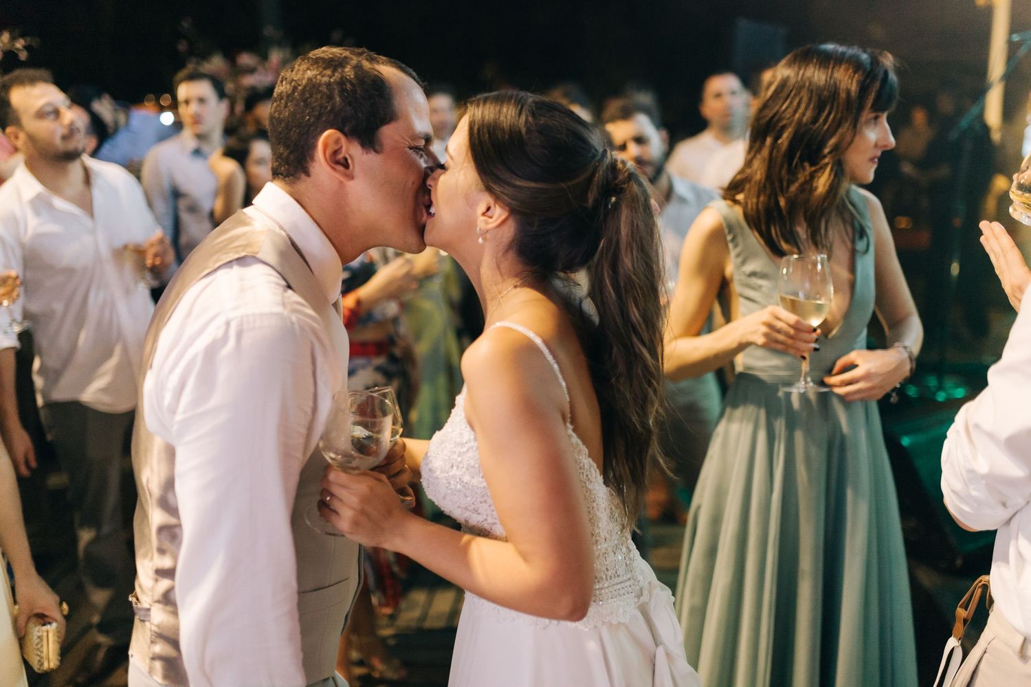 Wedding guests dancing together on a dimly lit dance floor during an evening reception celebration.