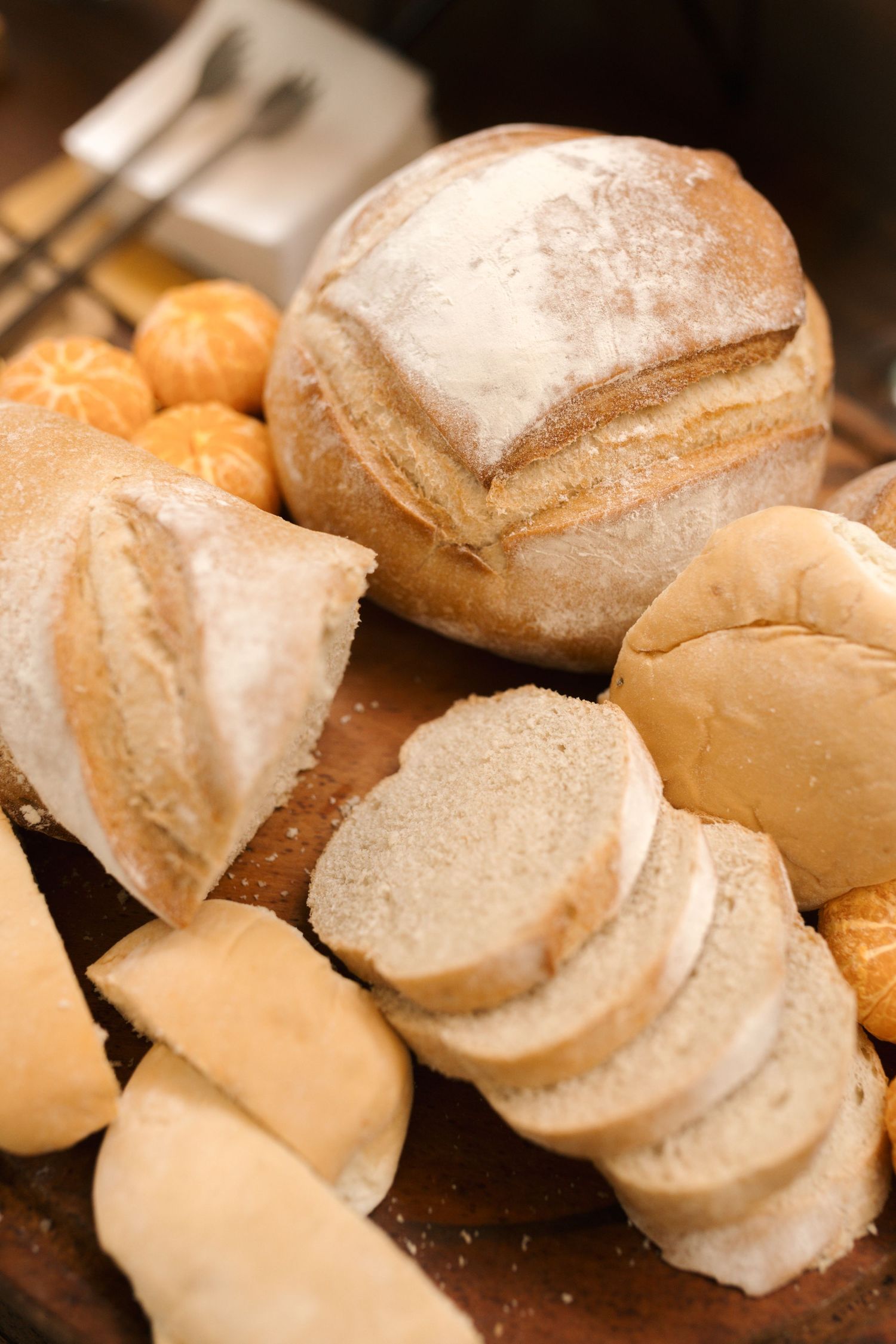 Fresh baked artisanal bread rolls dusted with flour on dark surface.