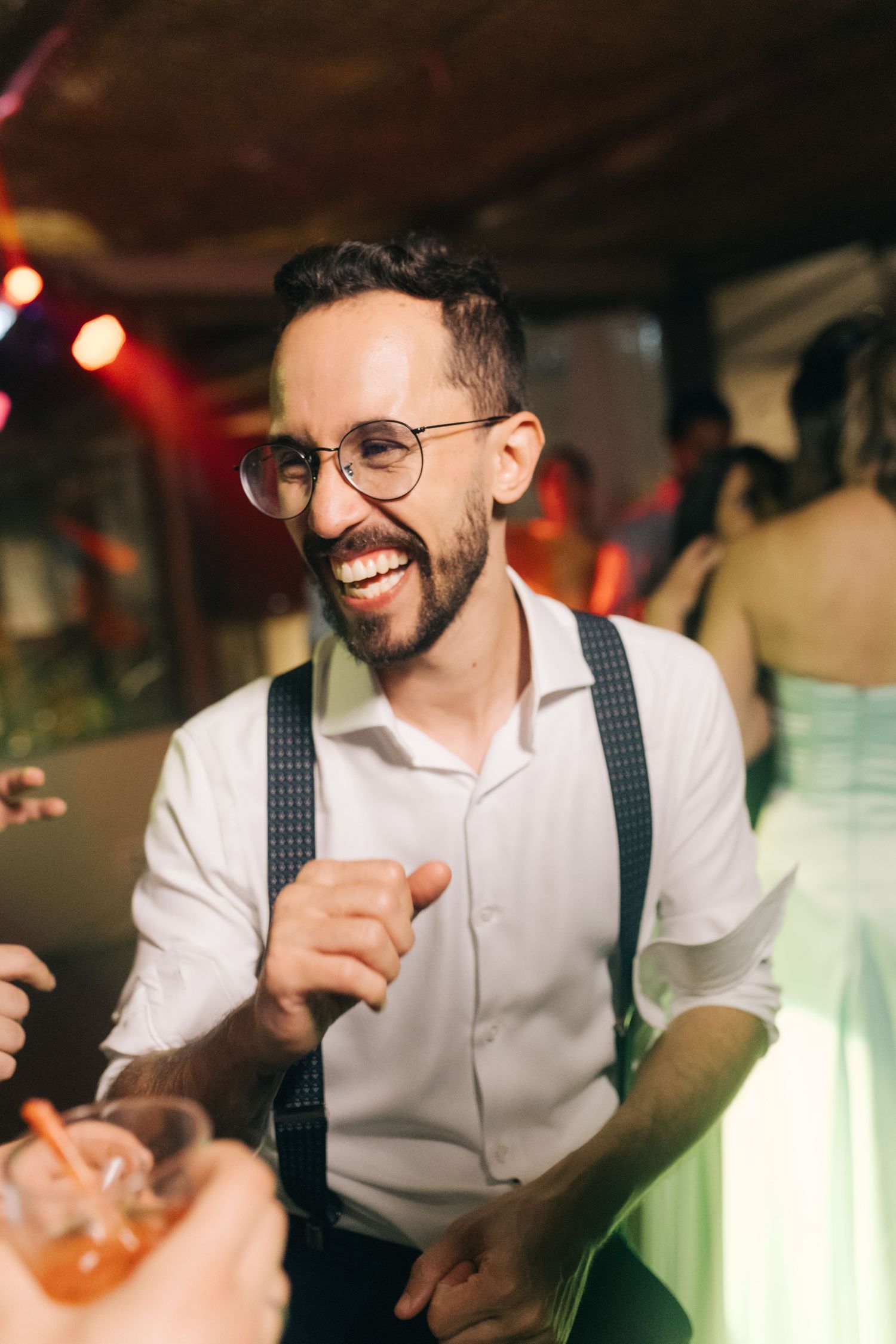 Guest enjoying lively moments at wedding reception in suspenders and white shirt.