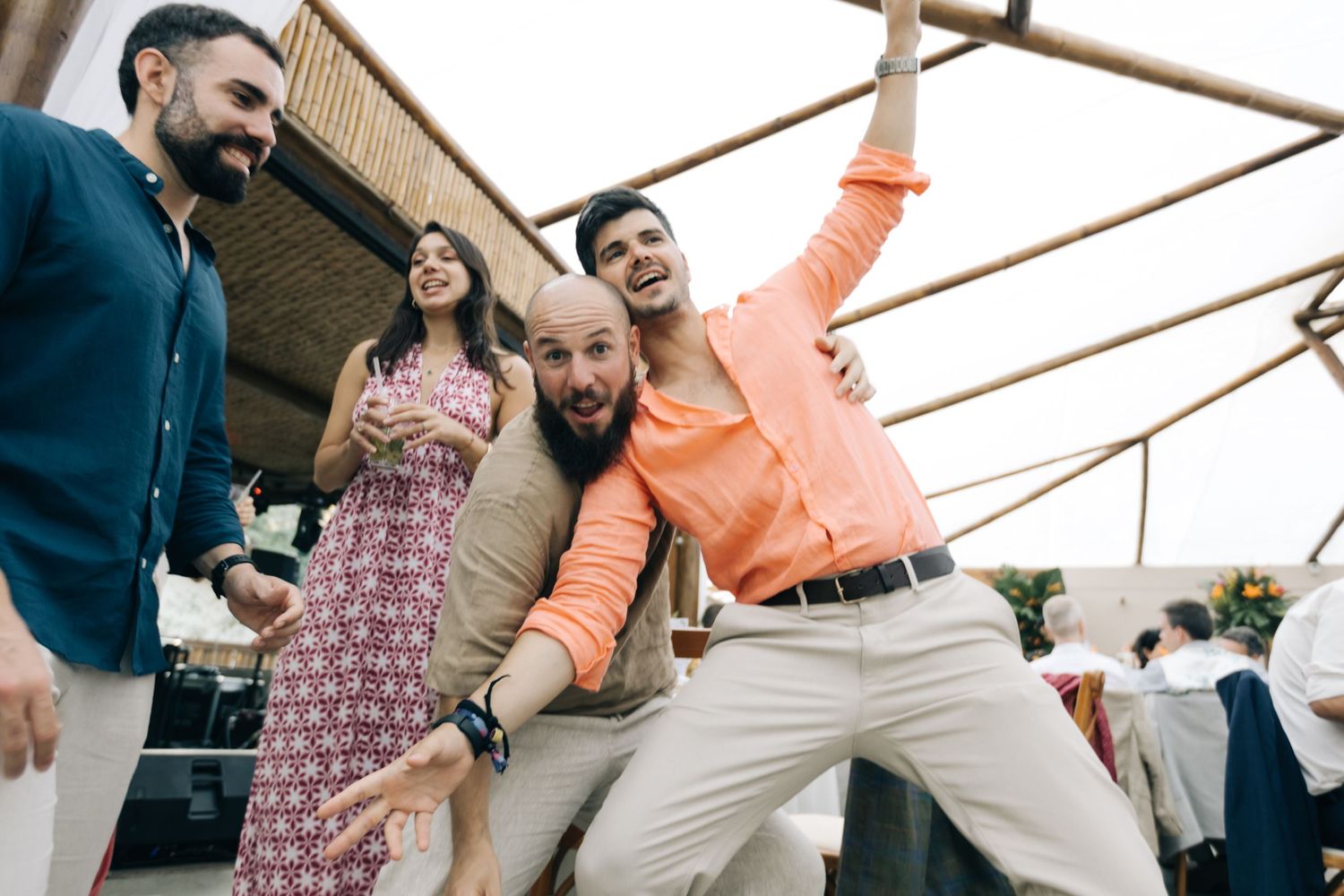Wedding guests dancing and celebrating with energetic moves at outdoor reception.