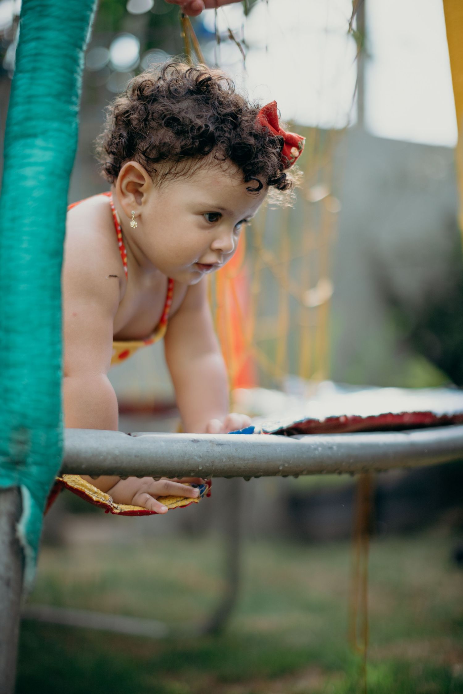 Child leaning over a teal-colored surface during outdoor play.