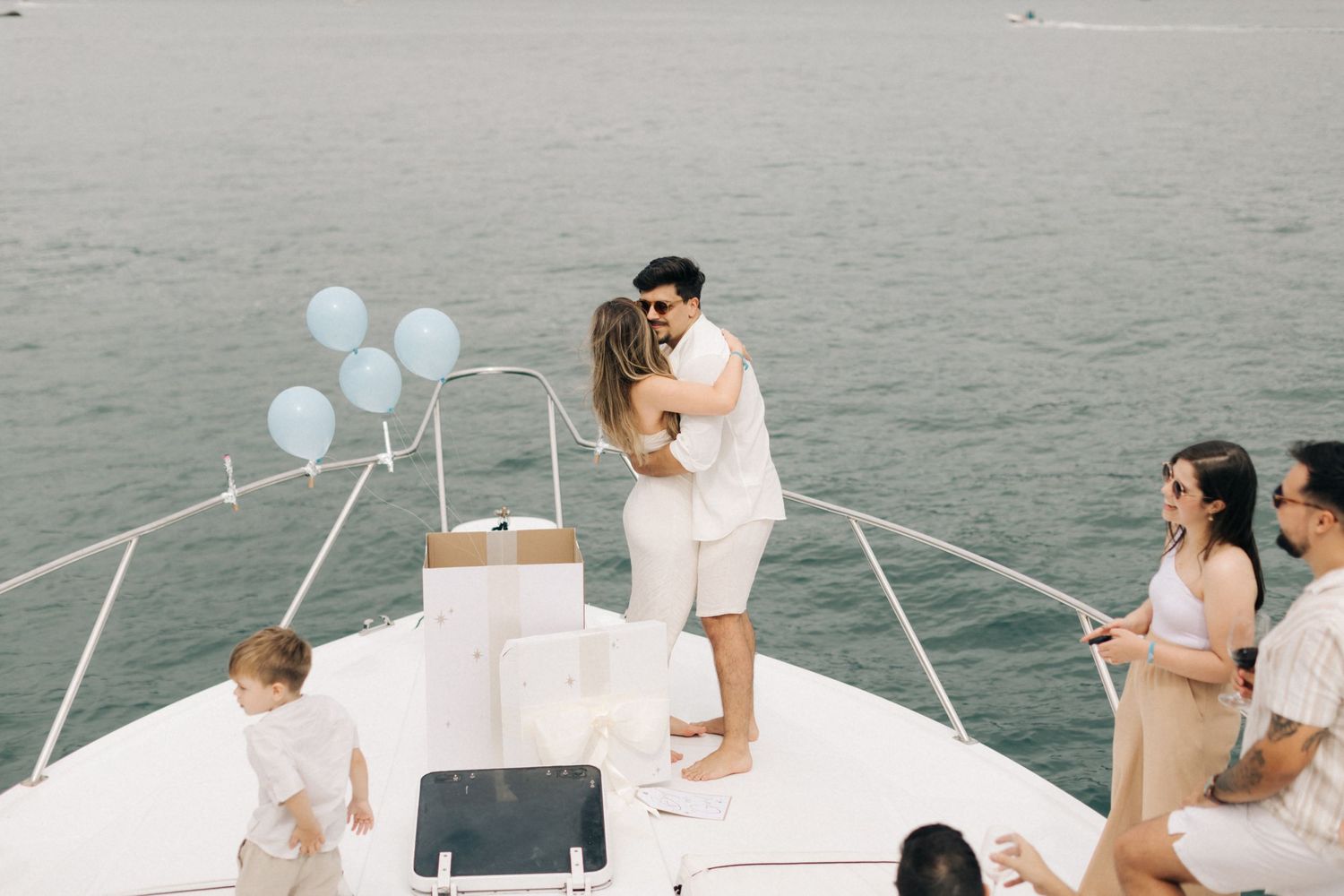 A tender moment shared on a yacht deck with guests and blue balloons in the scene.