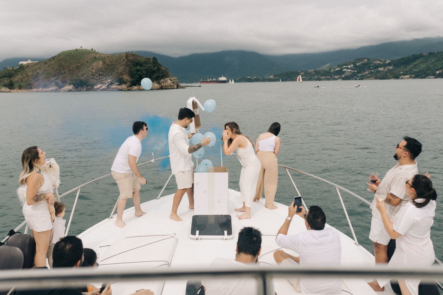 Boat passengers lounging on white deck with coastal mountain views.
