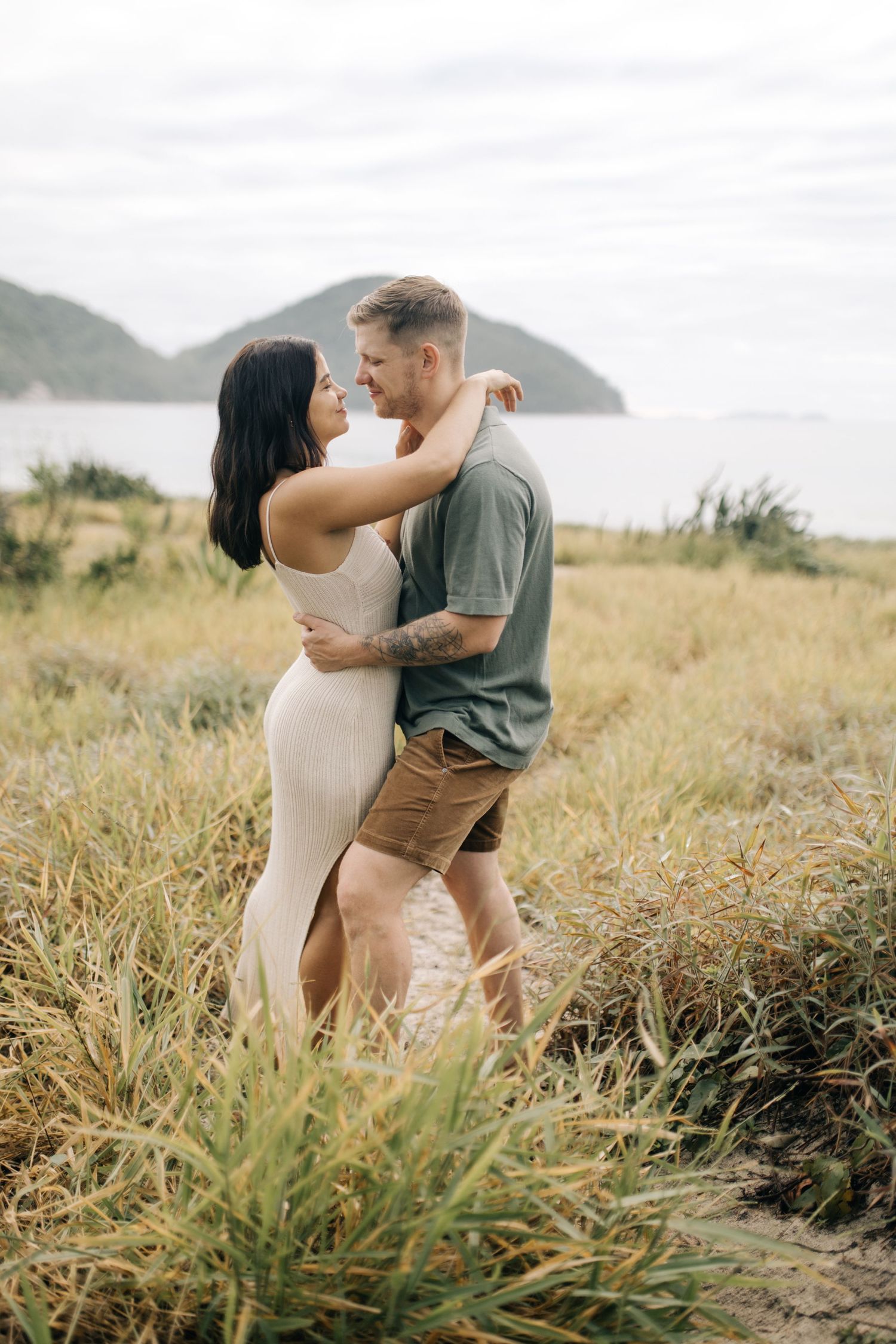 A couple shares tender moments together on a hillside overlooking a scenic mountain landscape.