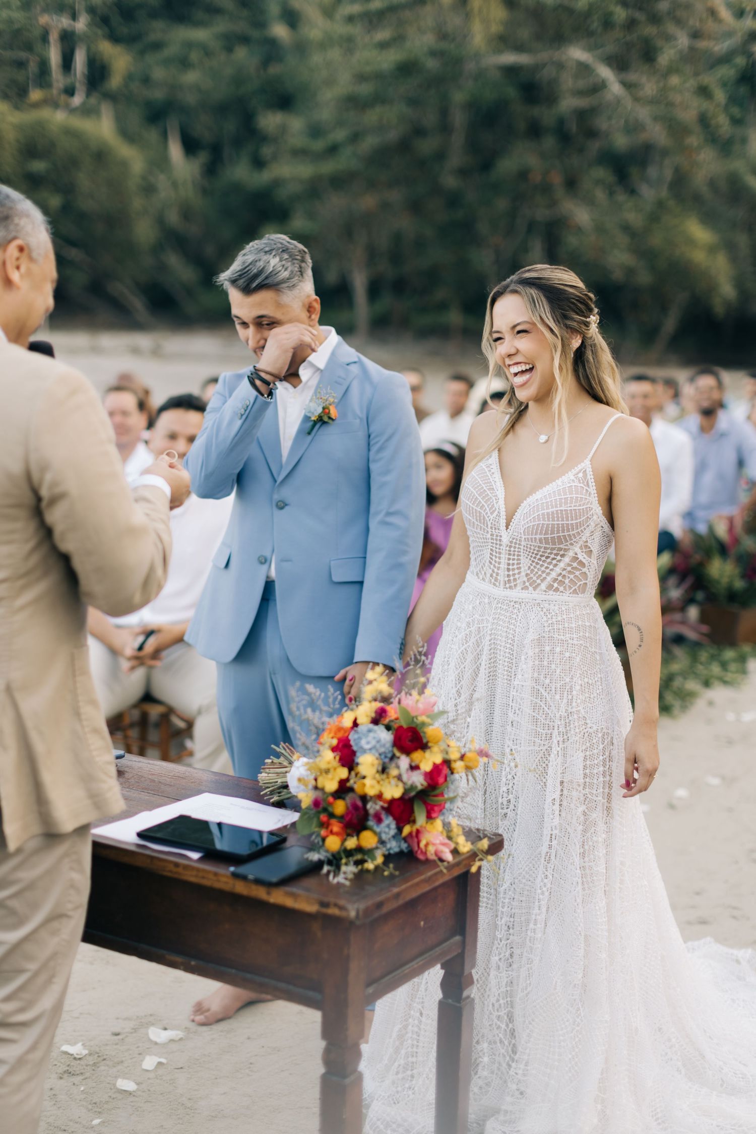 Outdoor wedding ceremony with a couple and officiant standing at a wooden table.