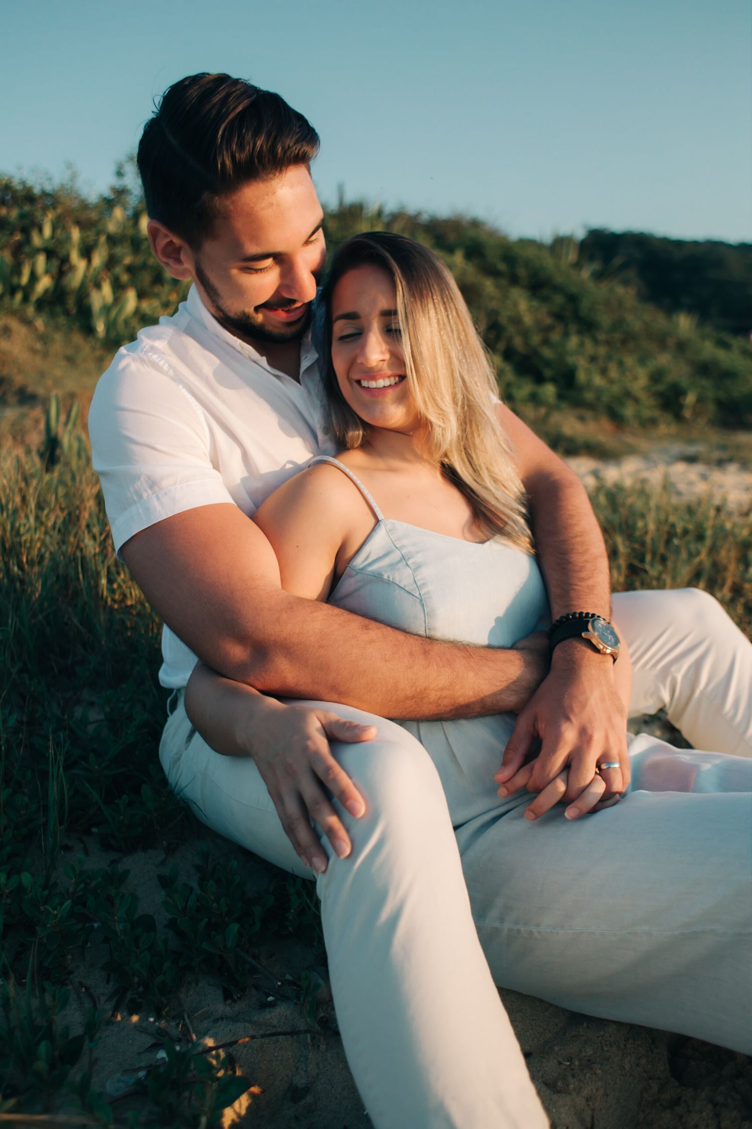 Intimate outdoor portrait of couple in white clothing sharing a joyful moment together.