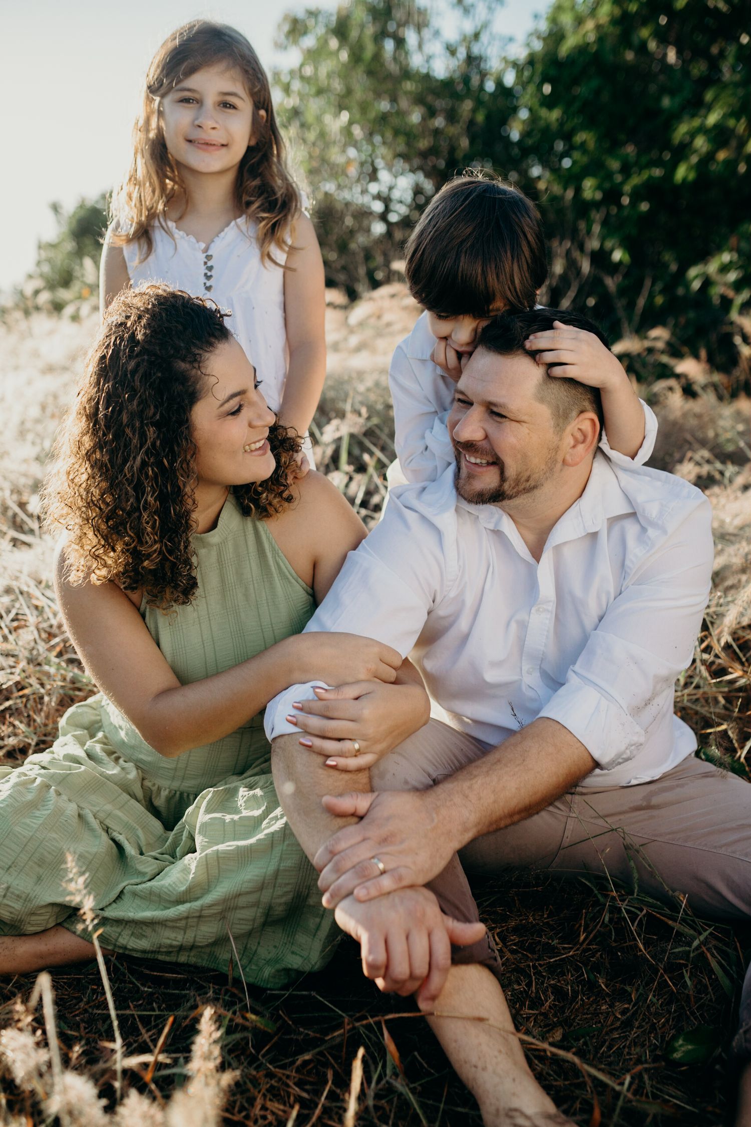 A couple shares an intimate moment outdoors in natural lighting while wearing casual clothing.
