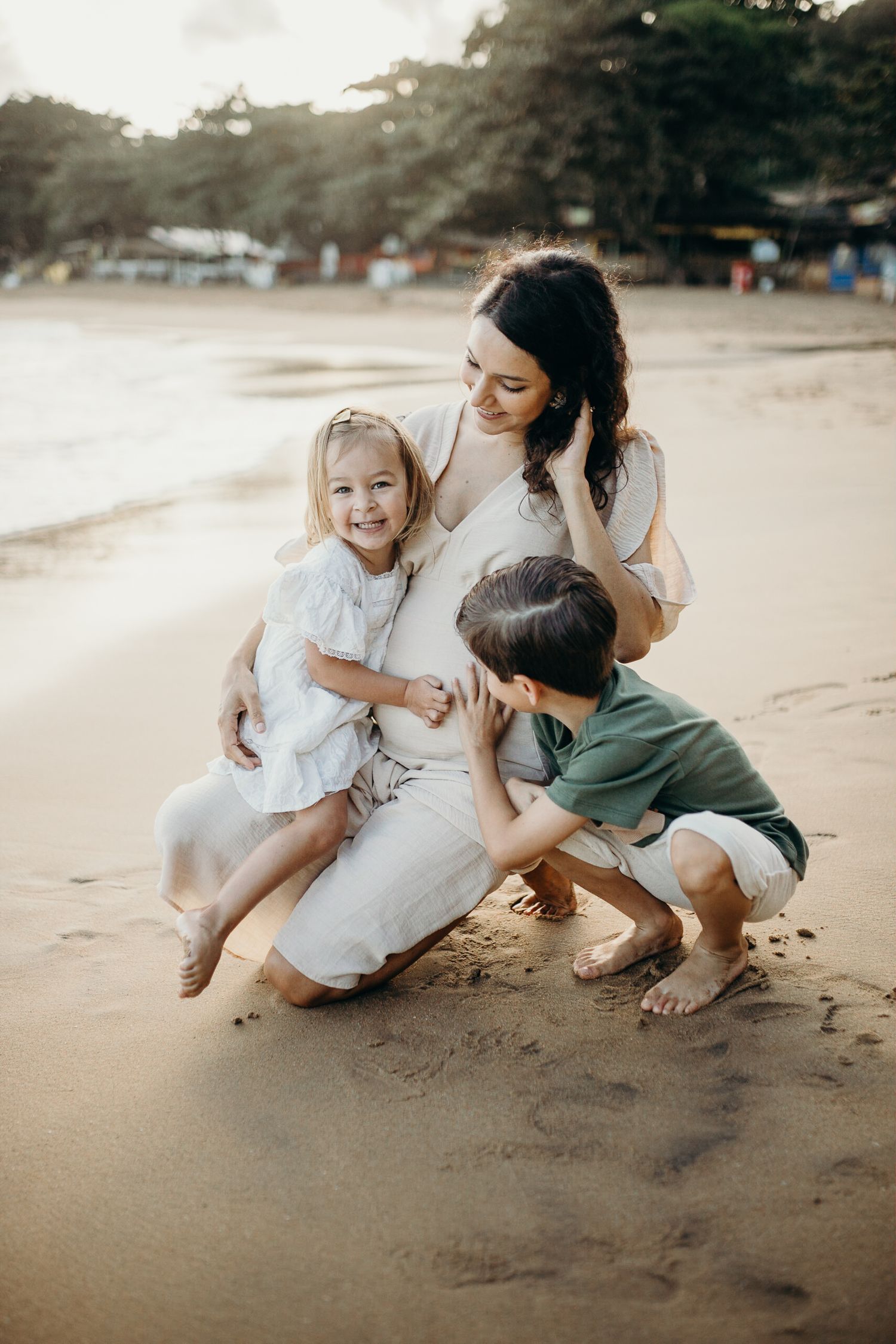 Family shares joyful moment playing together on sandy beach at sunset.