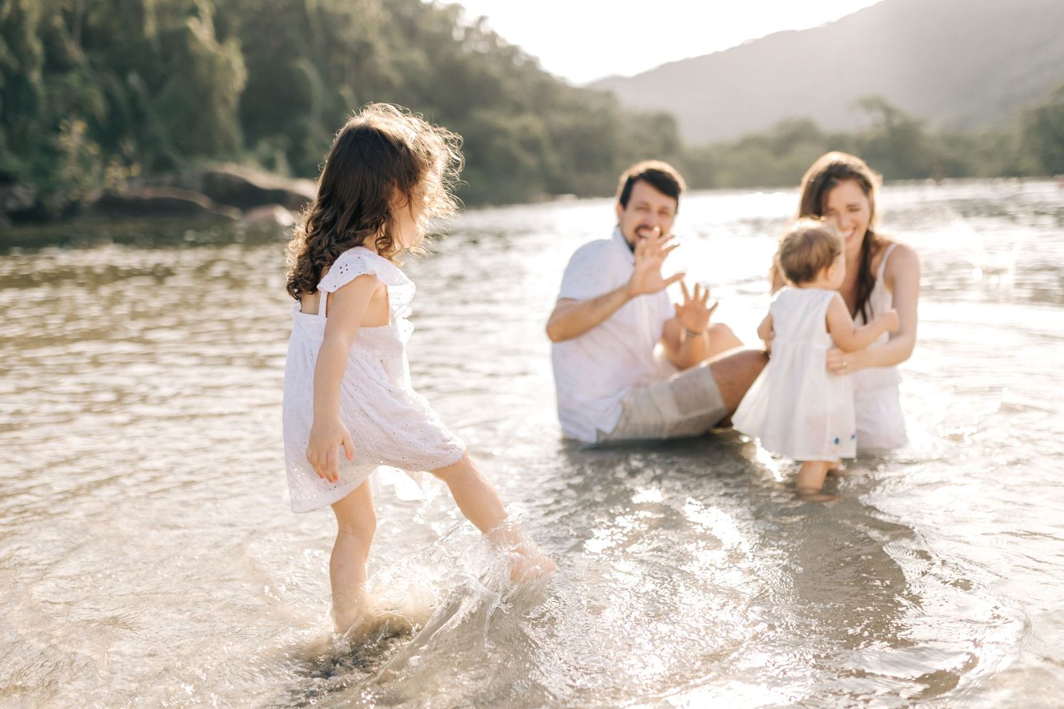 Carefree family splashing and playing in ocean water during sunset.