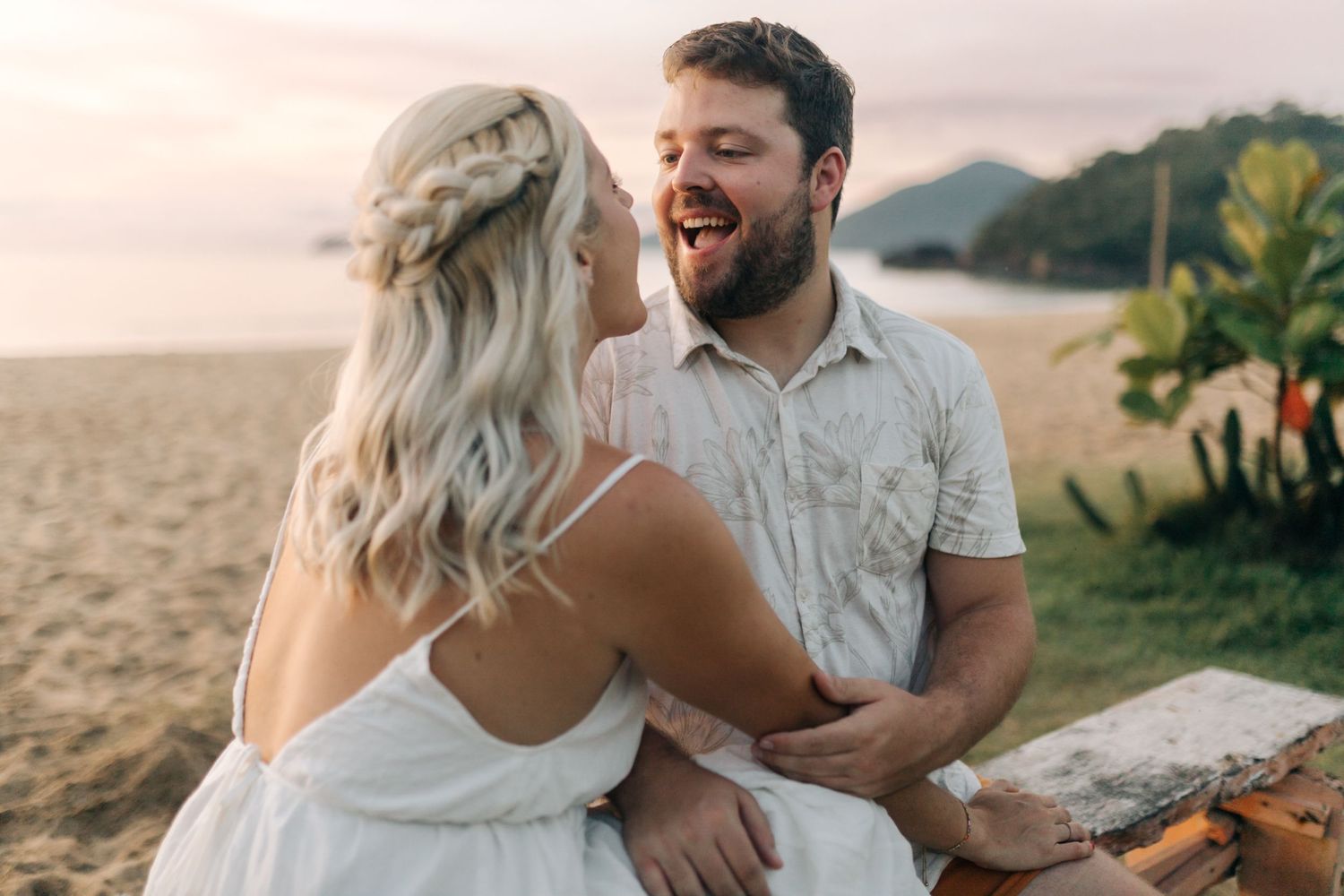 A joyful moment shared between a couple laughing together on a tropical beach.