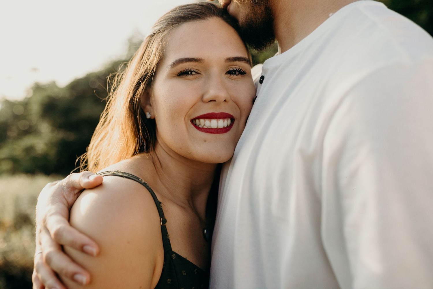 Romantic couple embraces in warm natural lighting during golden hour photoshoot.