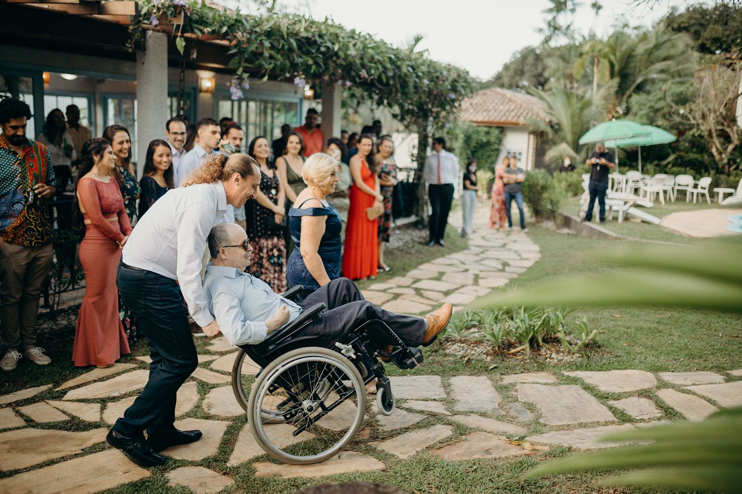 Group of wedding guests gathered on stone pathway in garden setting.